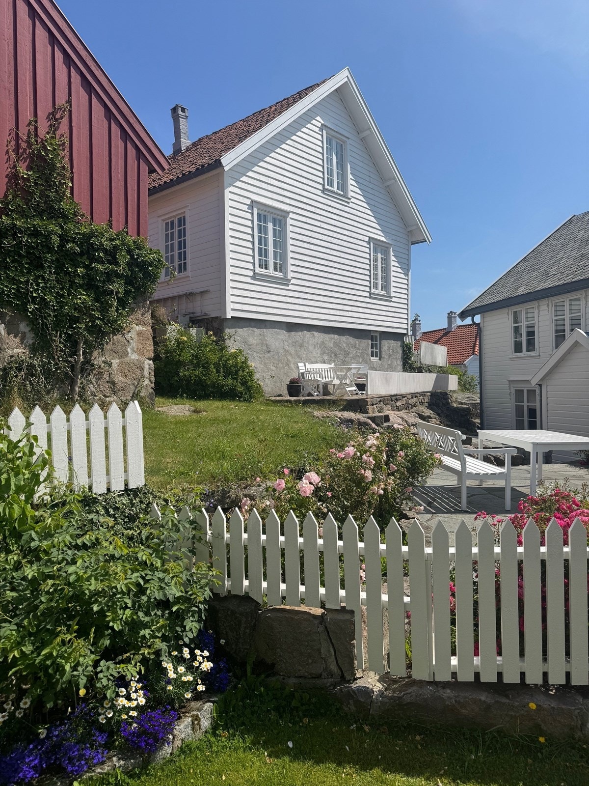 Den klassiske hvite trehusbebyggelse omgitt av steinsatte murer og rødmalte uthus. Galleribilde