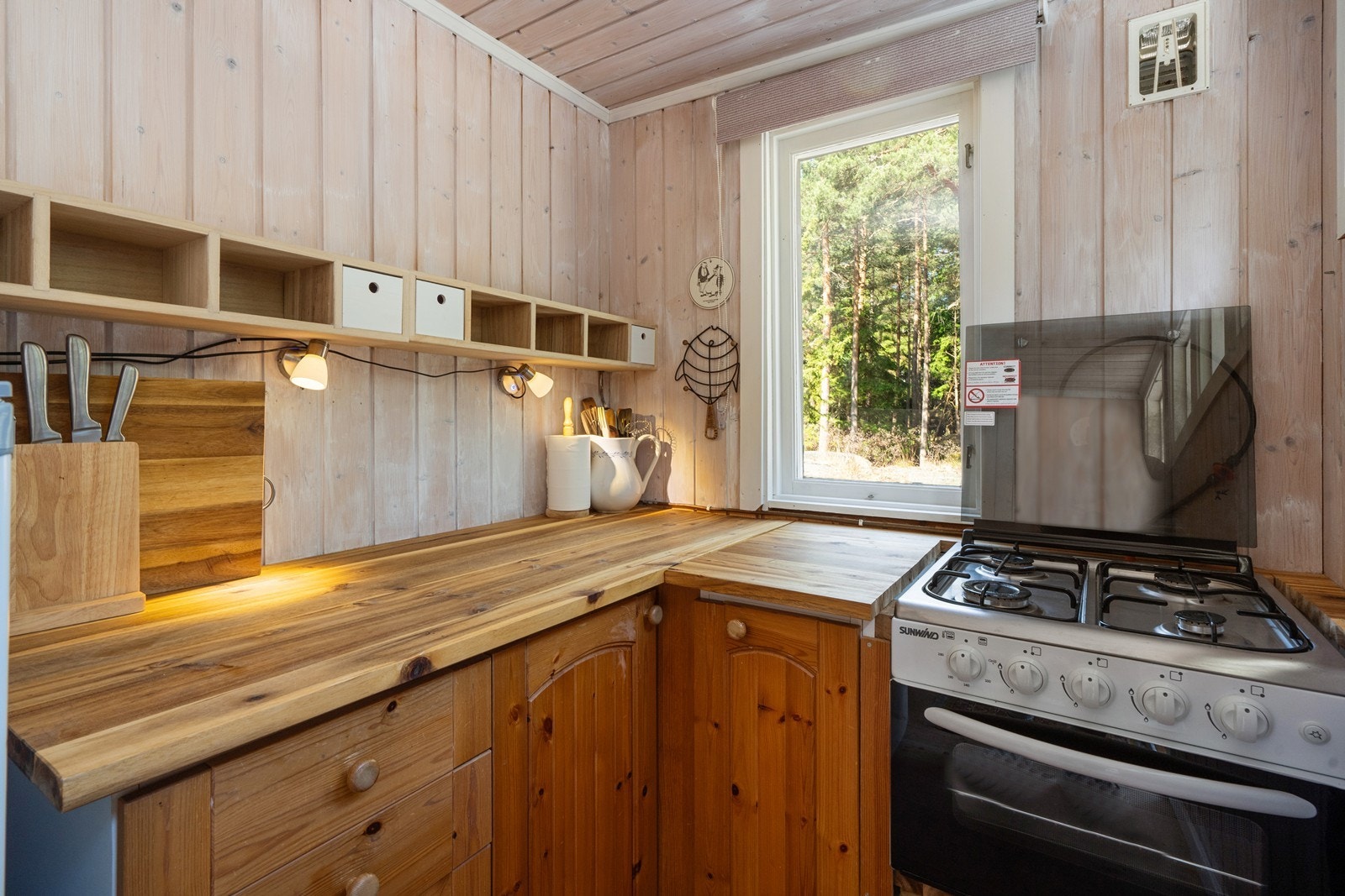 Kjøkkenet har en enkel innredning i furu med benkeplate i heltre og gasskomfyr. Galleribilde