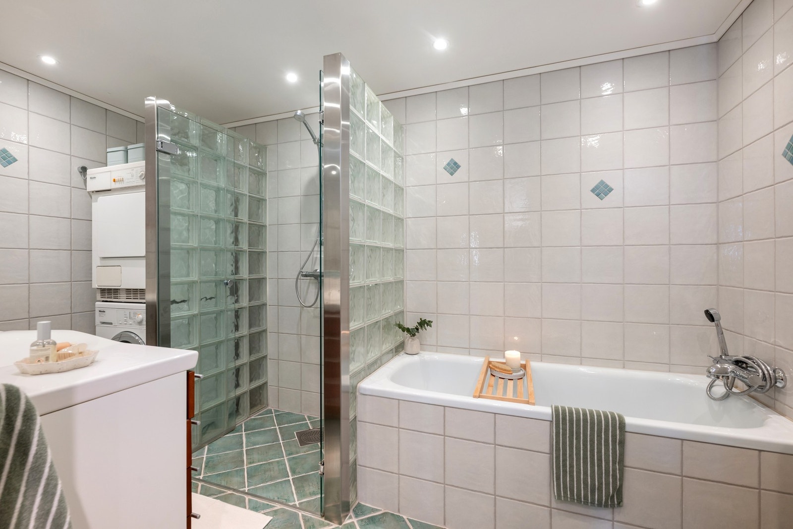 Bad 1 har adkomst fra soverom og er innredet med dusjnisje, innfliset badekar samt opplegg for vaskemaskin og tørketrommel. Galleribilde