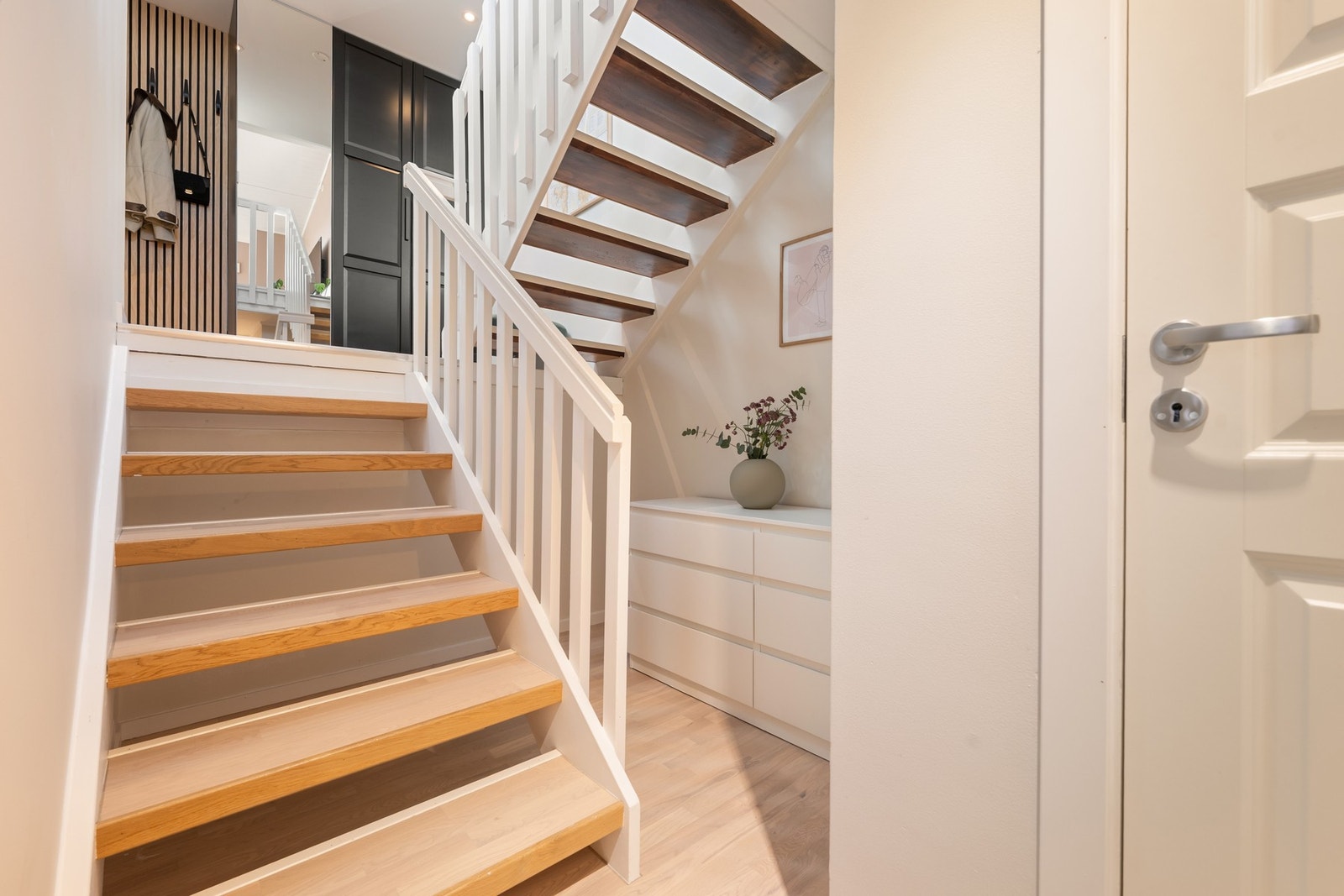 Pen trapp med åpne trinn belagt med parkett, med adkomst til praktisk bod og god oppbevaringsplass under trappen. Galleribilde