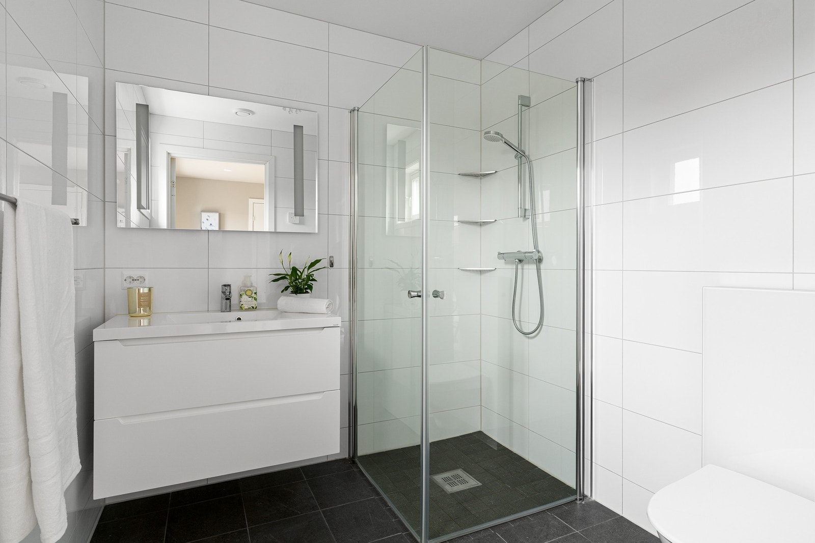 Badet i første etasje har en stilren kombinasjon av lyse veggfliser og mørke gulvfliser, og er utstyrt med gulvvarme. Galleribilde