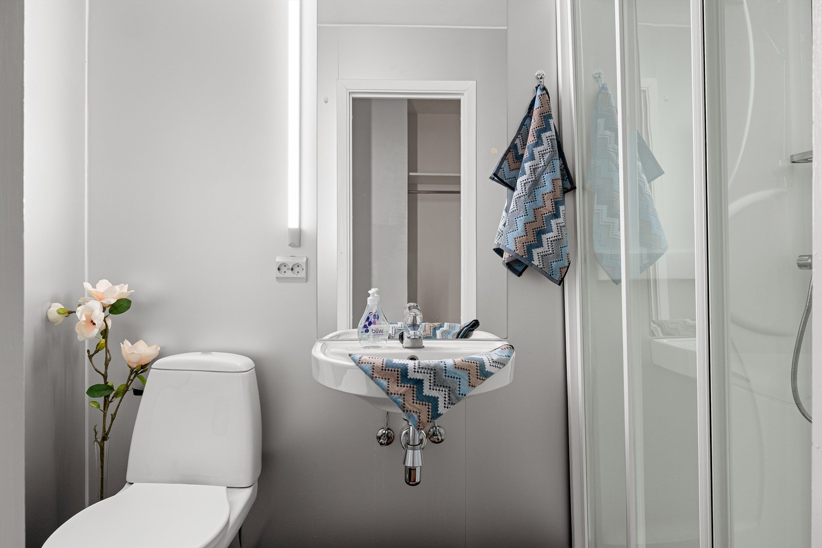 Badet fremstår som tidløst og er innredet med toalett, vegghengt servant og dusjkabinet. Galleribilde