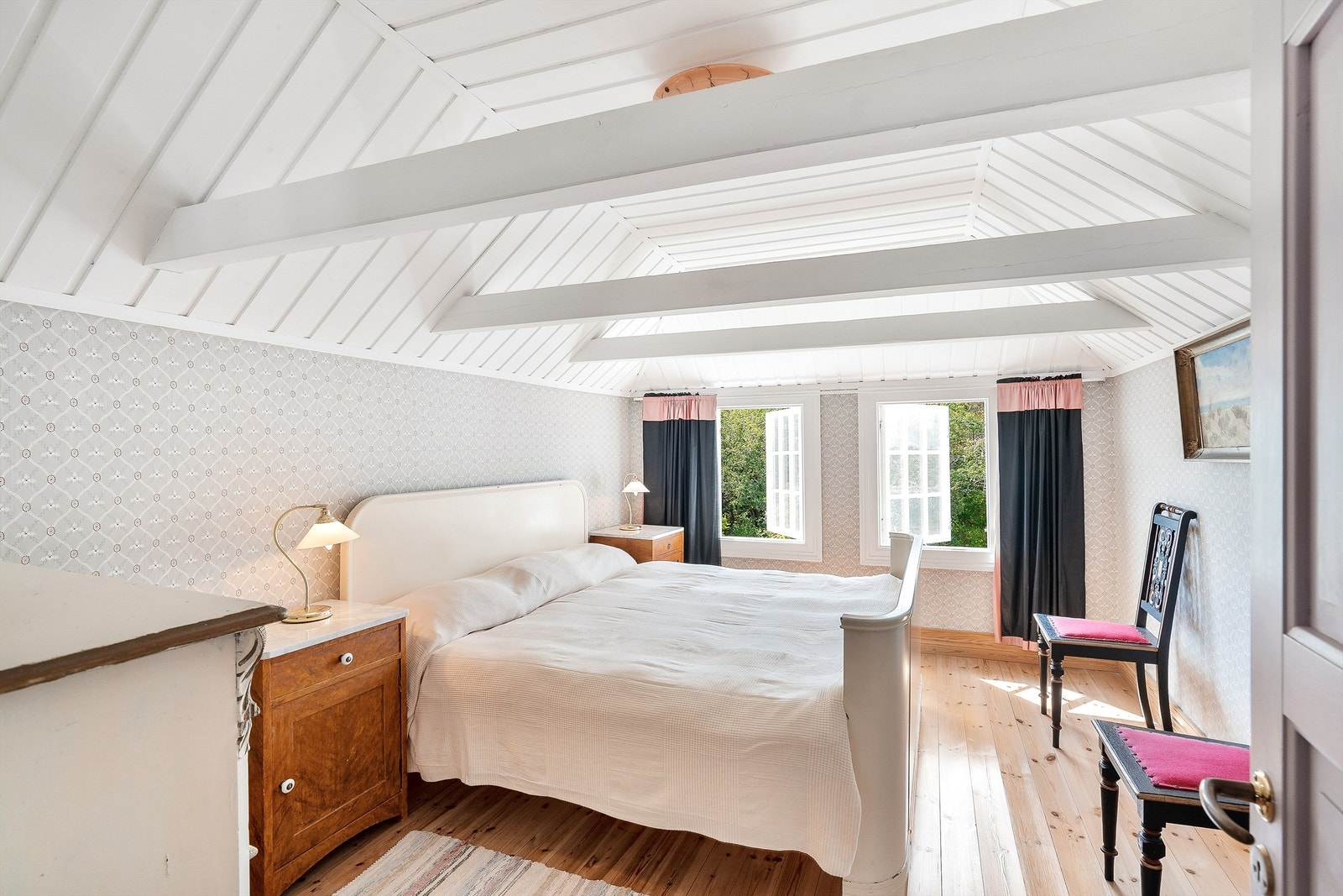 Stort soverom med lyse overflater og naturlige takbjelker. Galleribilde