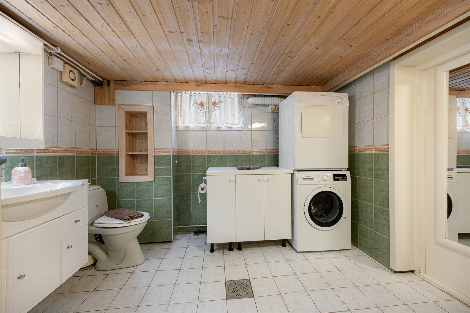 Badet i kjelleren har flislagt gulv og praktisk opplegg for vaskemaskin. Galleribilde