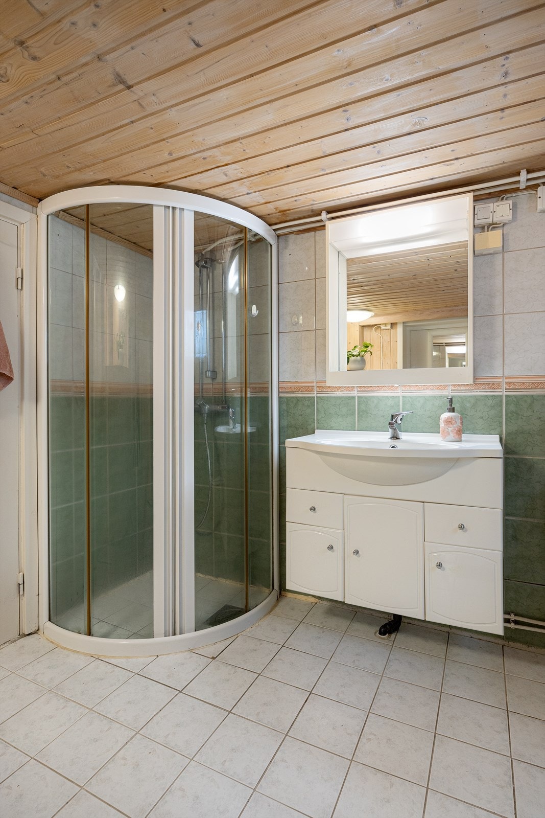 Badet er utstyrt med dusjhjørne med dører, servantinnredning og toalett. Galleribilde