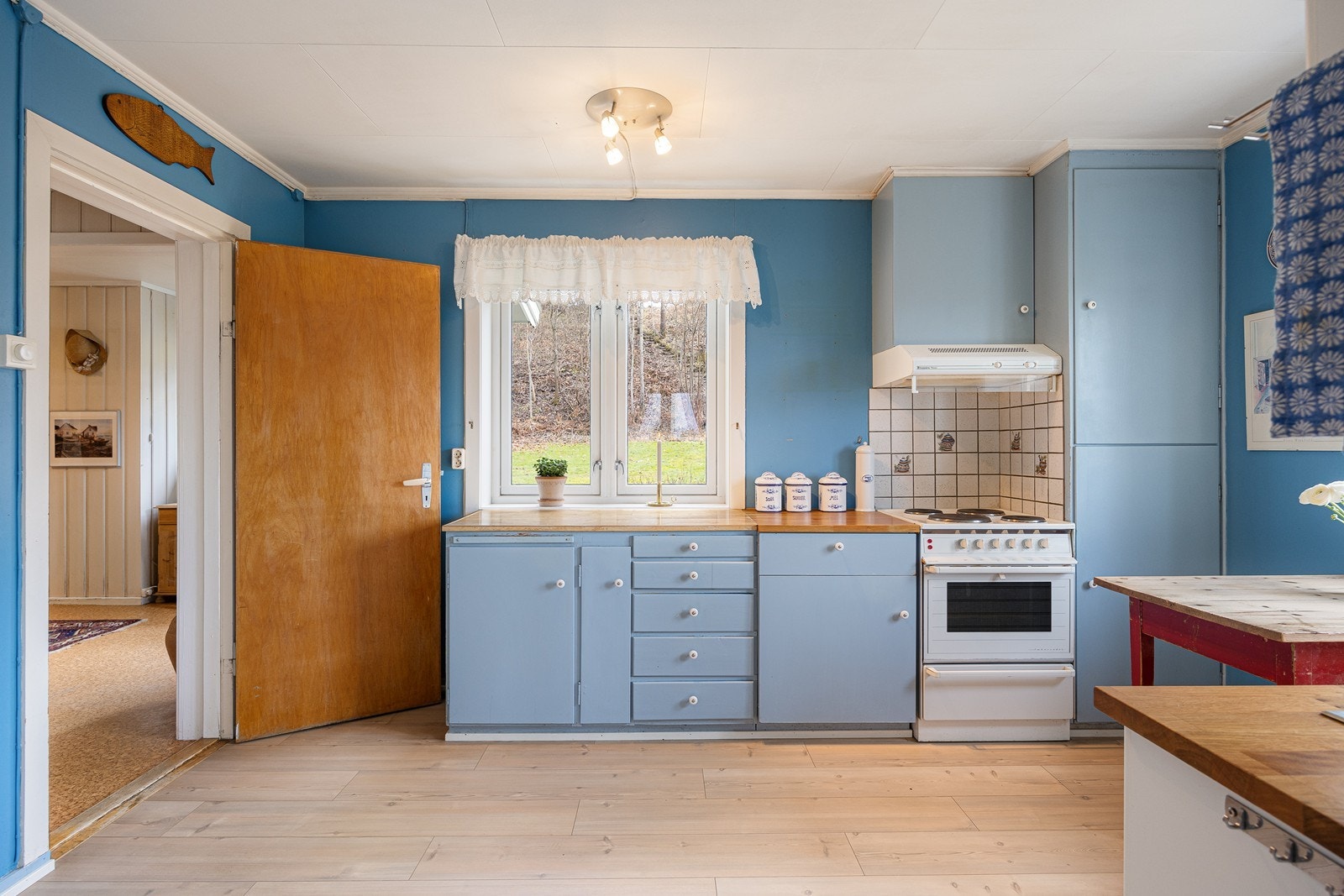 Kjøkkenet har en landlig sjarm med heltregulv og blåmalte vegger. Galleribilde