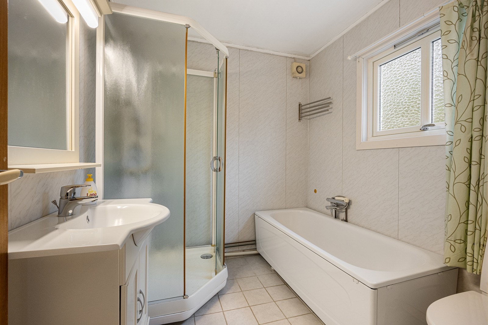 Badet er holdt i en lys fargevalør og har både dusjkabinett og badekar med dusjløsning. Galleribilde