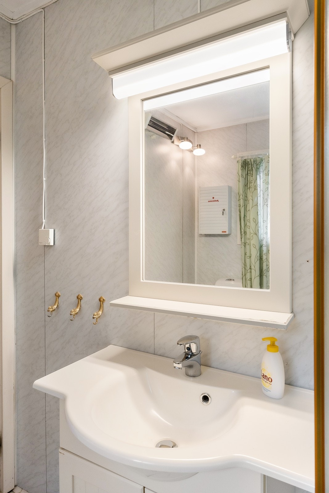 Innredningen består av et hvitt servantskap og speil med tilhørende lys. Galleribilde