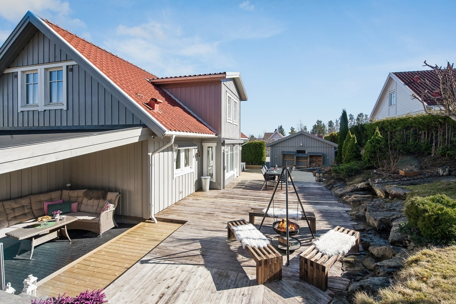 Den store terrassen strekker seg rundt deler av huset og har flere soner for utemøbler. Galleribilde