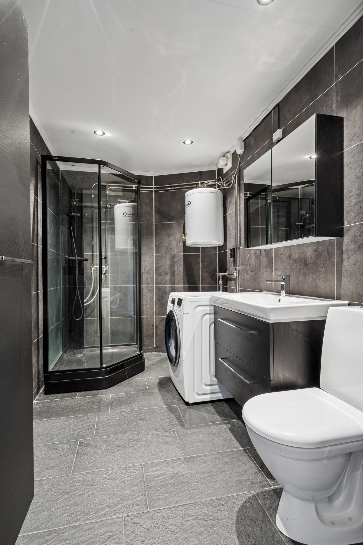 Badet ble oppgradert i 2019 og har innredning med nedfelt sevant, speilskap, toalett, dusjkabinett og opplegg for vaskemaskin Galleribilde