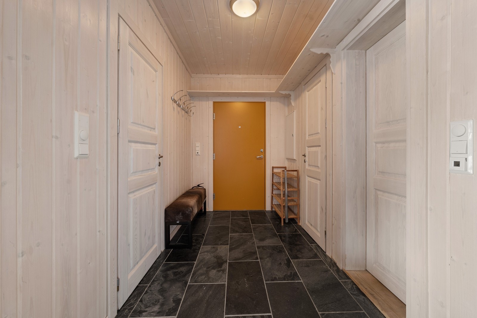 Entre/gang med garderobe og praktiske hyller til slalomsko, skisko og kurver til å oppbevare ting i. Med skifer på gulv kan en trygt gå inn med våte sko Galleribilde