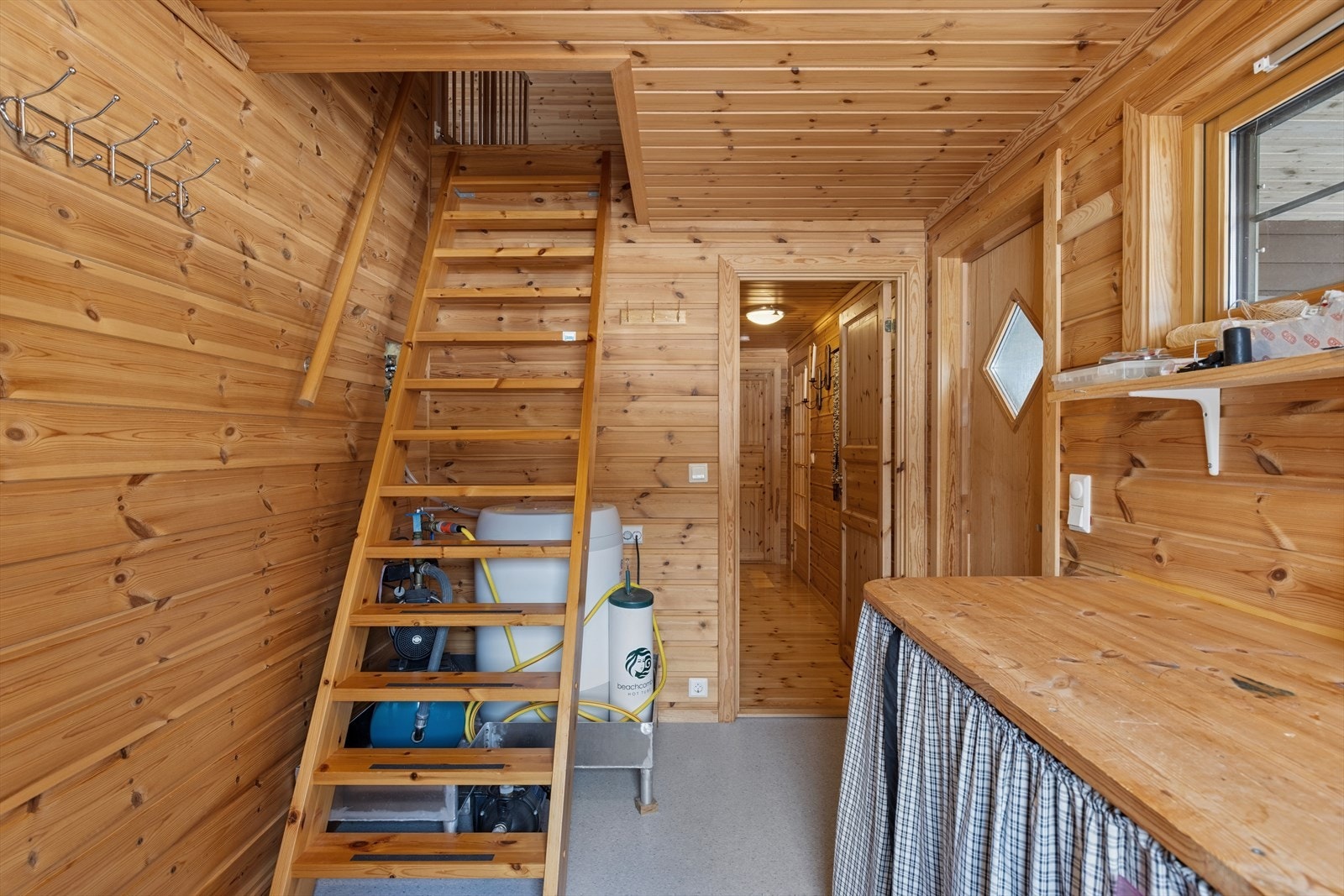En trapp i lakkert furu leder opp til loftstuen. Vann hentes fra egen brønn med pumpe. Galleribilde