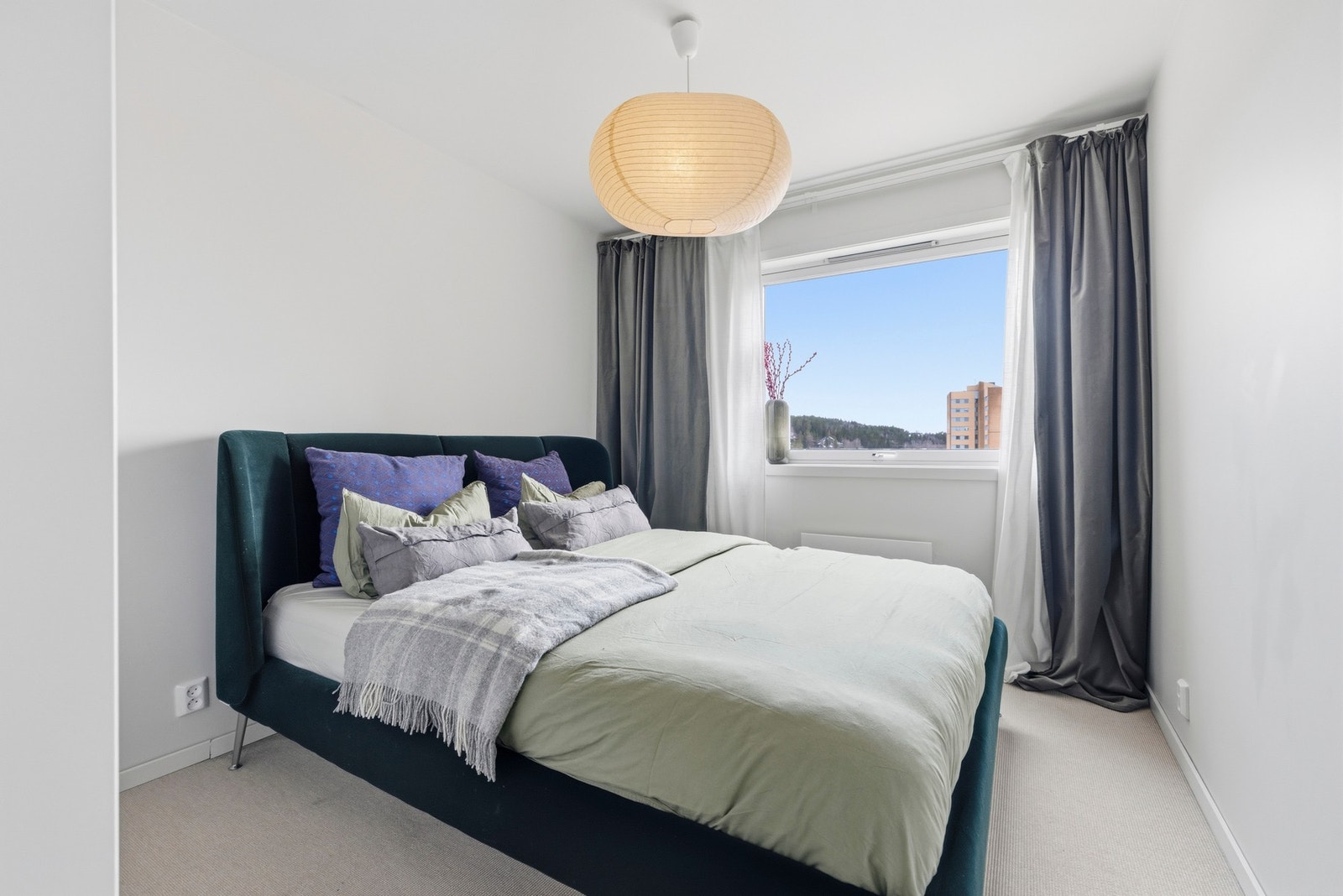 Leiligheten har et luftig og romslig soverom med teppe på gulvet og lyse vegger Galleribilde