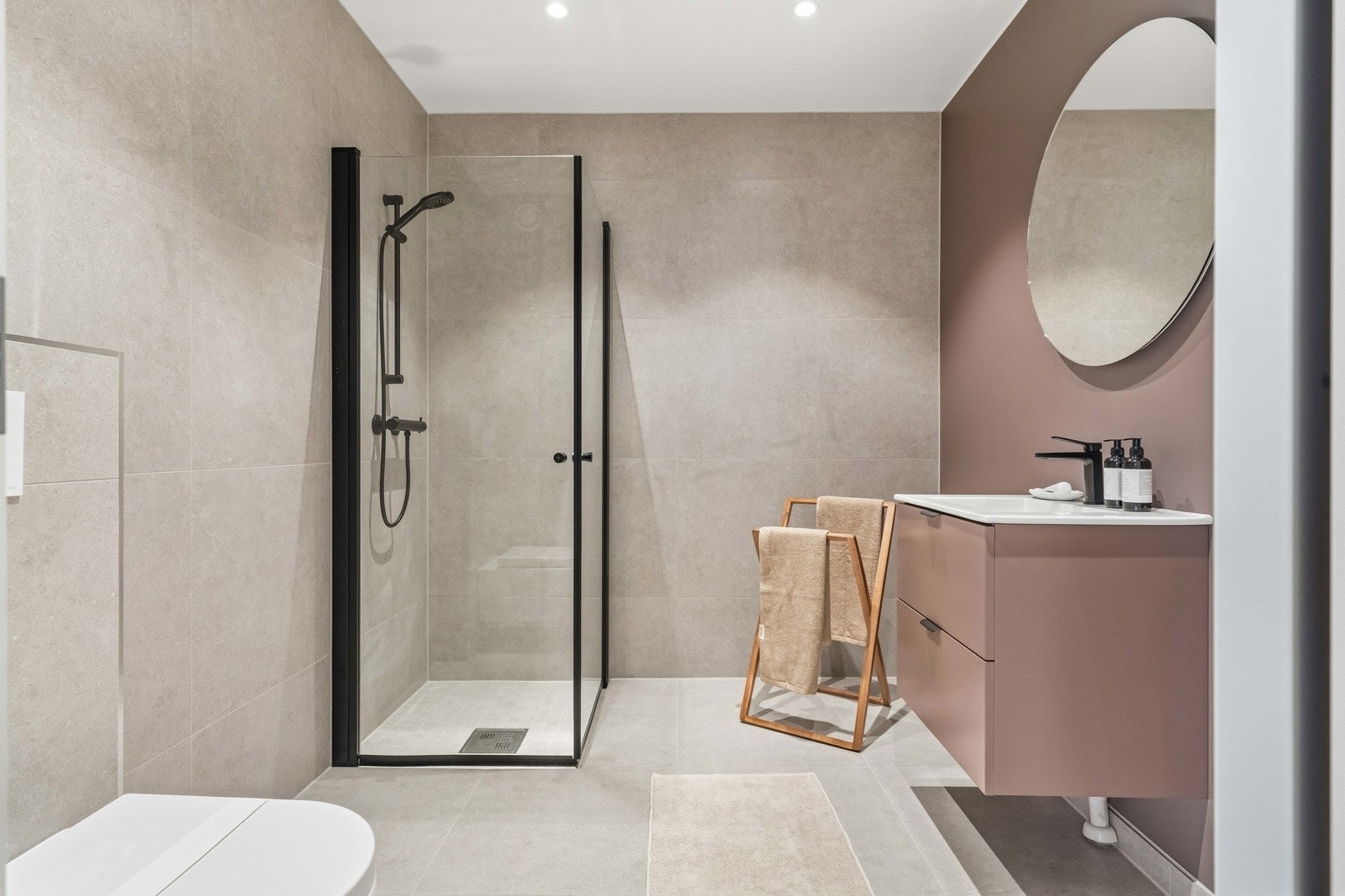 Badet har en stilren og moderne utforming med flislagte overflater, varmekabler i gulv og en gjennomført materialbruk. Galleribilde