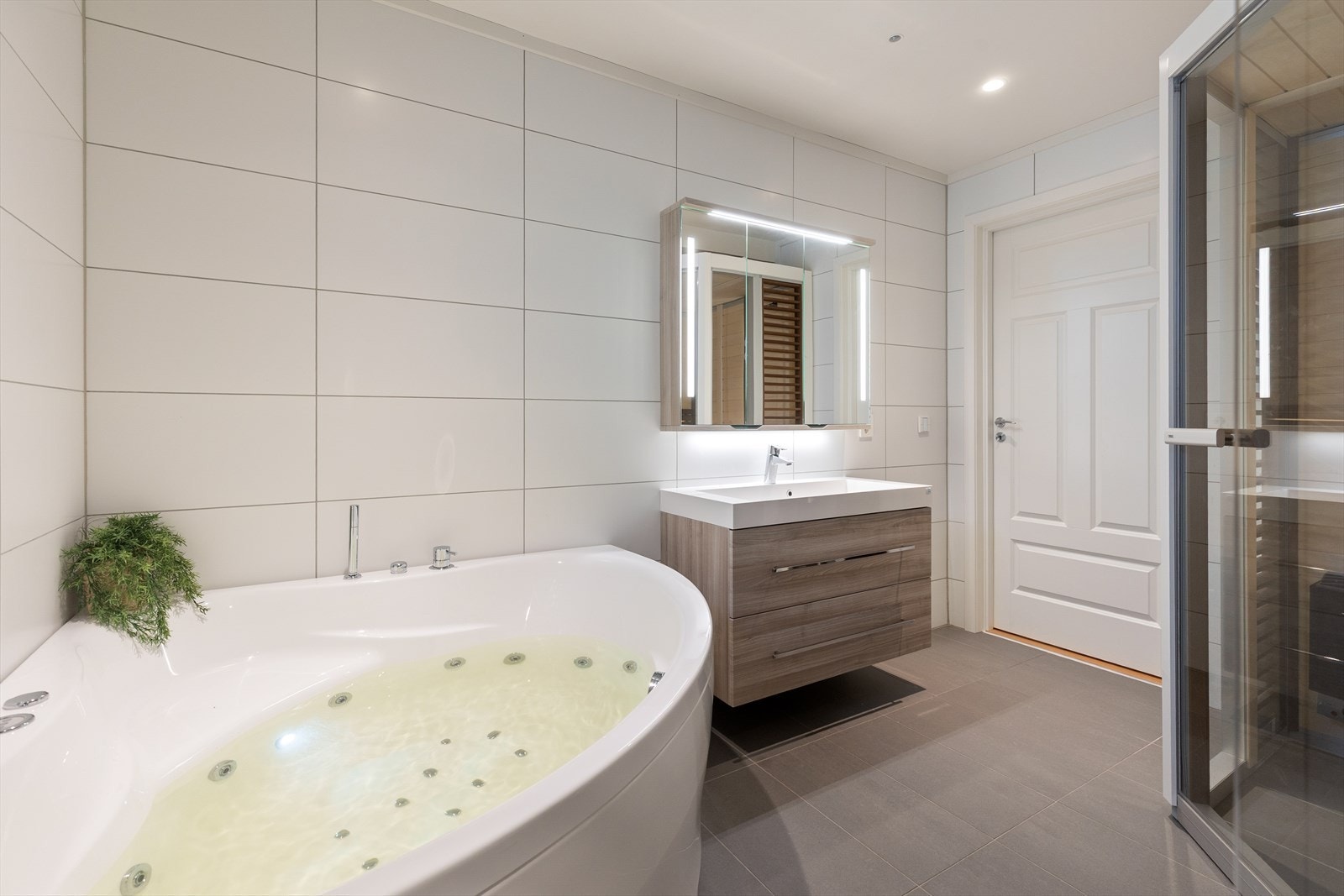 Rommet har baderomsinnredning med nedfelt servant, speilskap med lyslist og veggmontert toalett. Badet er også utstyrt med massasjekar. Galleribilde