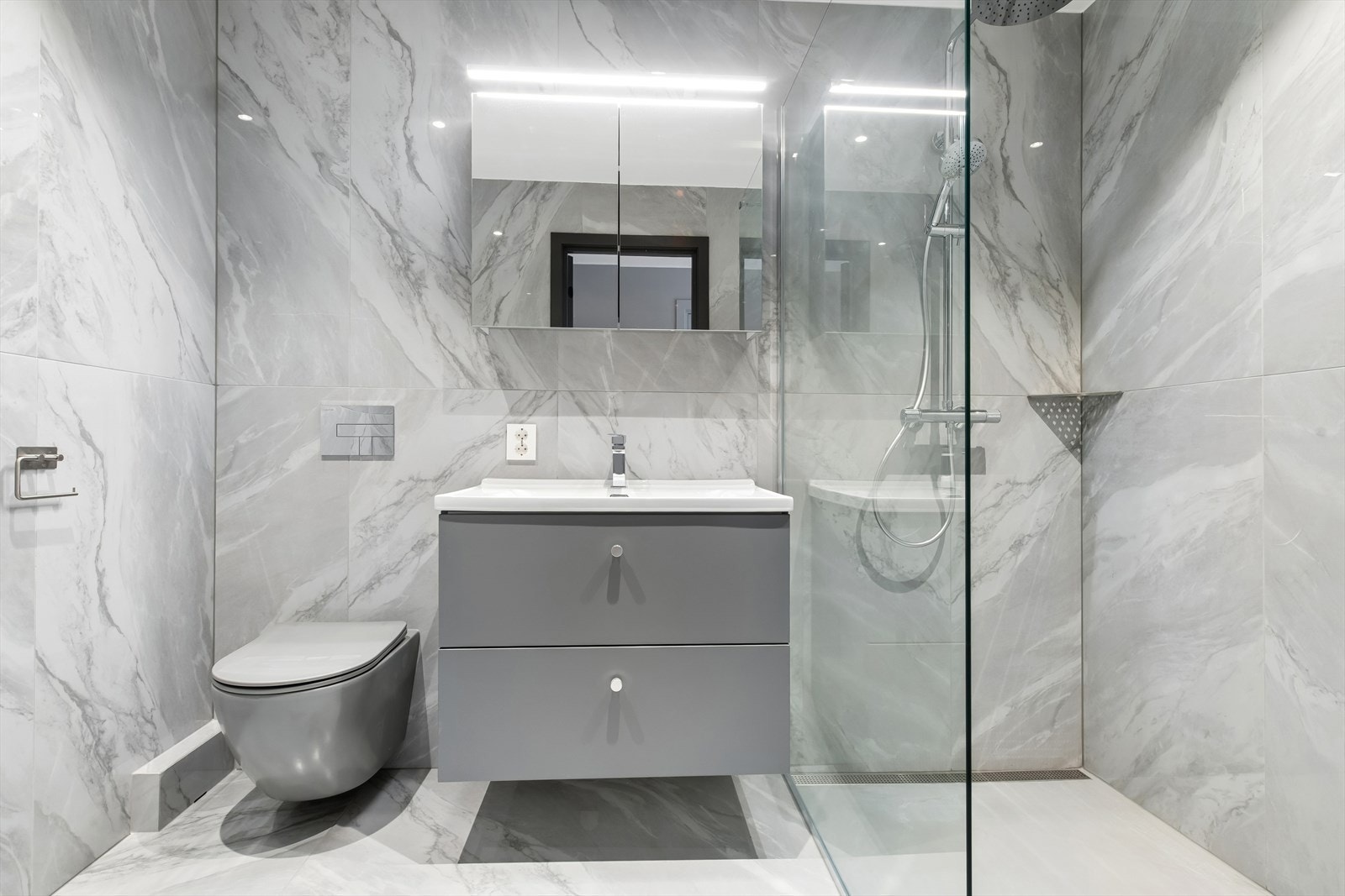 Stilrent bad/vaskerom fra 2026 med fliser på både gulv og vegger, samt behagelig gulvvarme. Galleribilde