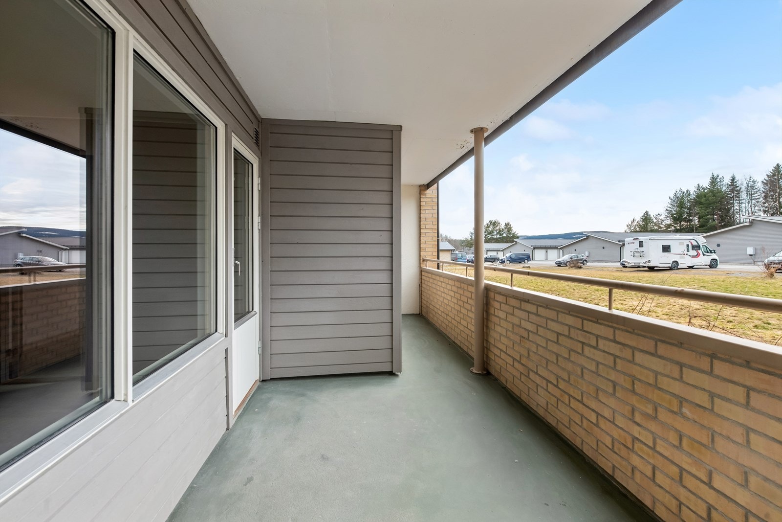 Takoverbygget veranda med malt betonggulv og rekkverk i teglstein og god plass til utemøbler. Galleribilde