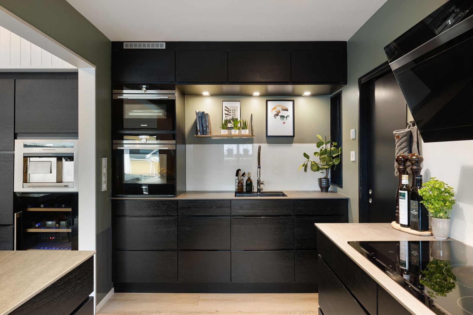 Kjøkkeninnredningen har mørke, slette fronter og laminert benkeplate, med glassplate mellom over- og underskap som gir et tidløst og lettstelt uttrykk. Galleribilde