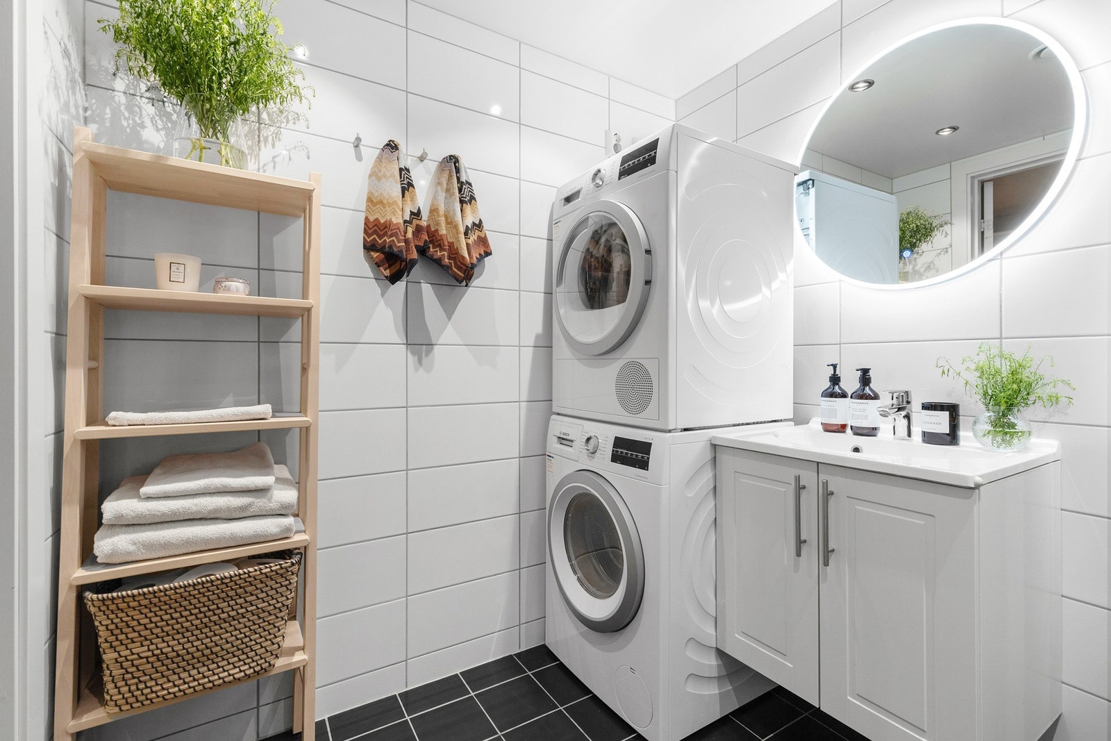 Rommet er innredet med nedsenket vask med innredning og speil samt opplegg for vaskemaskin og tørketrommel Galleribilde