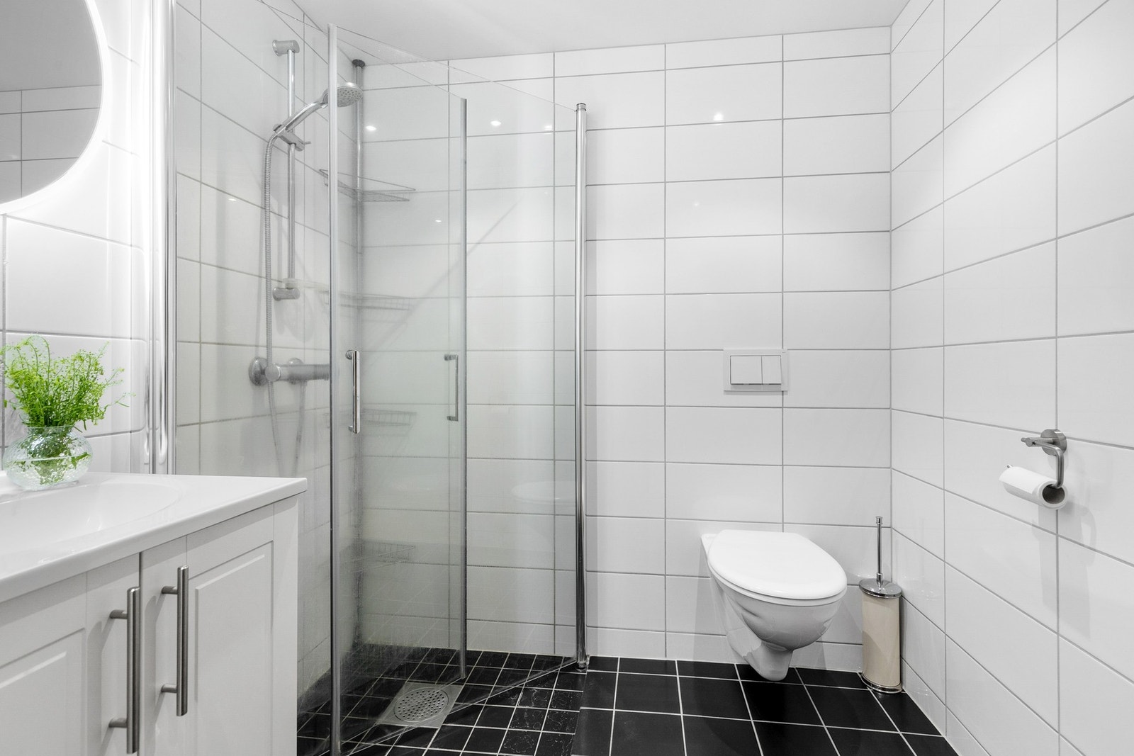 Videre er badet utstyrt med vegghengt toalett og dusjhjørne med innfellbare glassdører Galleribilde