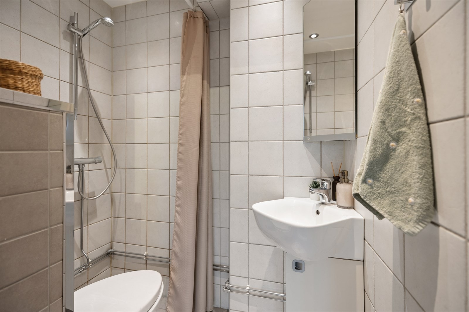 Bad/wc består av vegghengt wc, servant m/underskap, overskap m/speilfront og åpen dusj m/forheng. Galleribilde