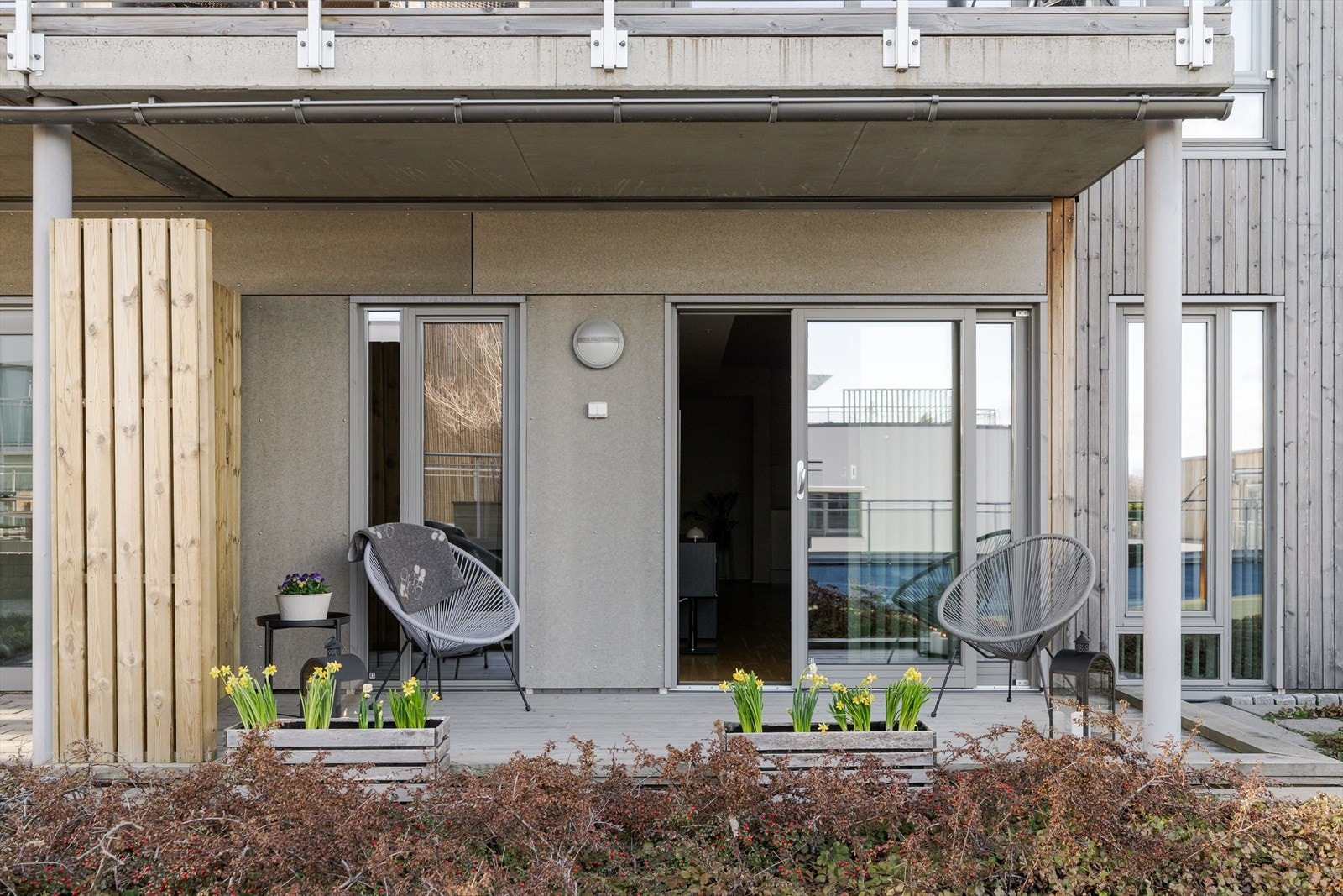 Fra stuen er det utgang til en solrik terrasse, skjermet av lav beplantning i forkant. Galleribilde