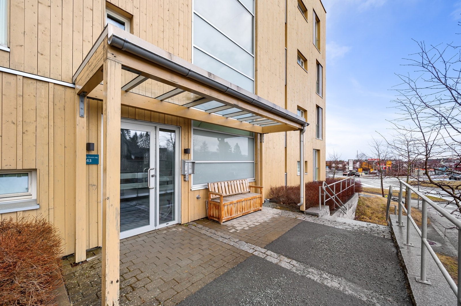 Innbydende og skjermet inngangsparti med overbygg og sitteplass. Galleribilde