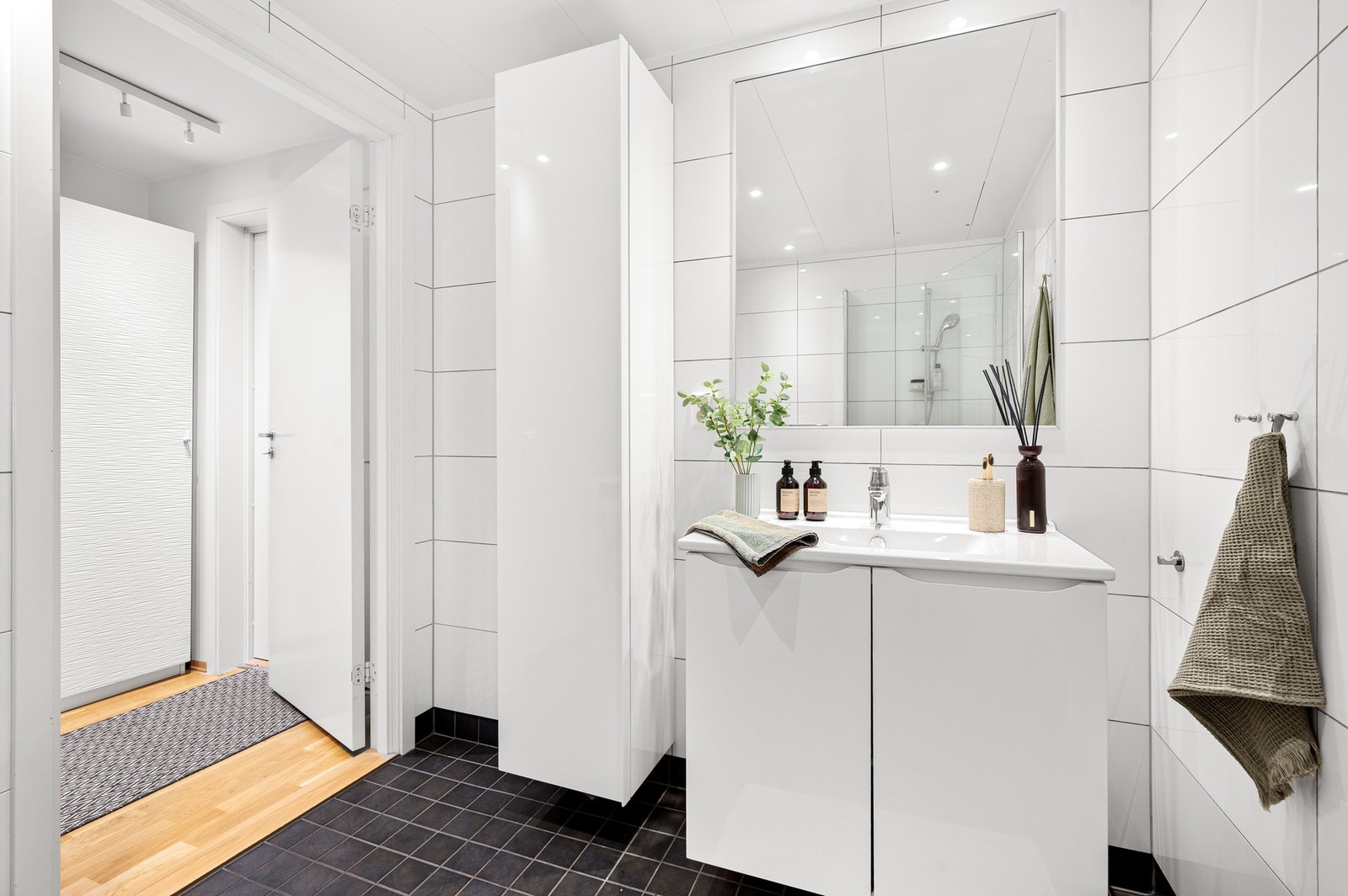 Badet har en praktisk innredning. Servant m/ underskap, speil og høyskap. Galleribilde