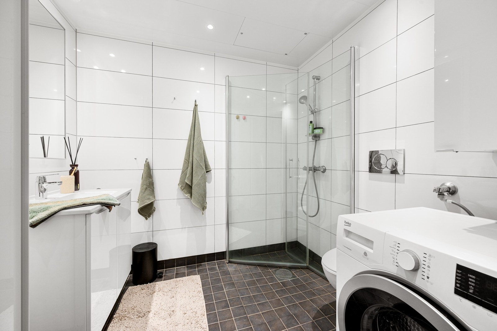 Flislagt bad med moderne uttrykk og praktisk planløsning. Elektriske varmekabler i gulv. Galleribilde