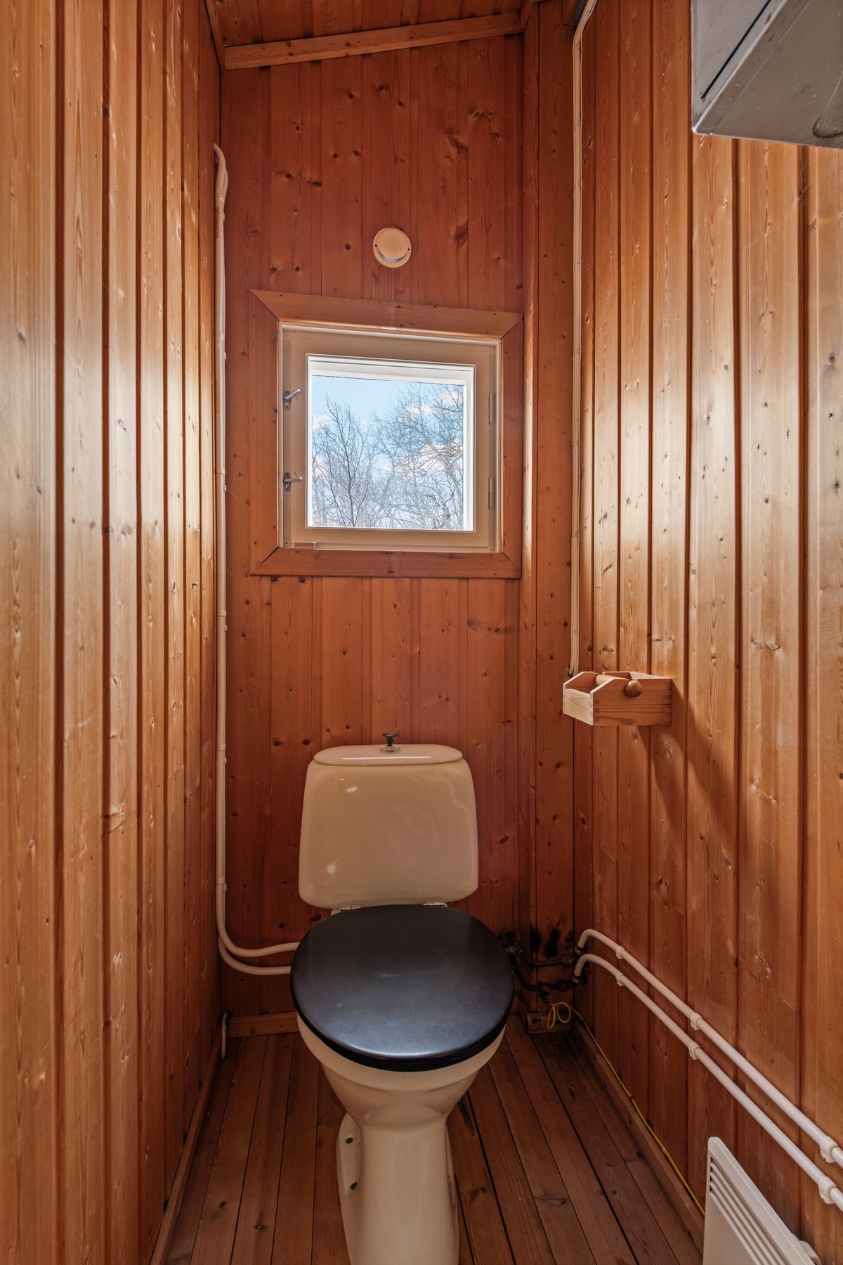 Toalettrom med panelvegger og et lite vindu for naturlig lys. Galleribilde