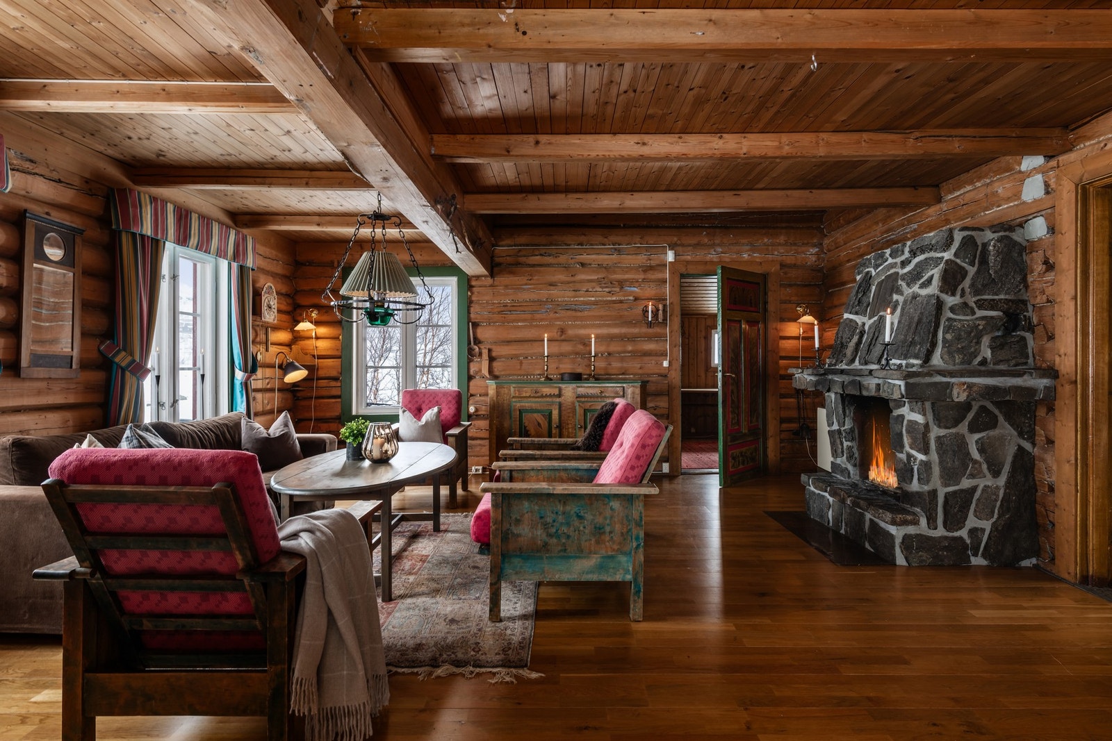 Lun og innbydende stue med solide tømmervegger, vakre detaljer og peis som skaper en varm og hyggelig atmosfære. Galleribilde