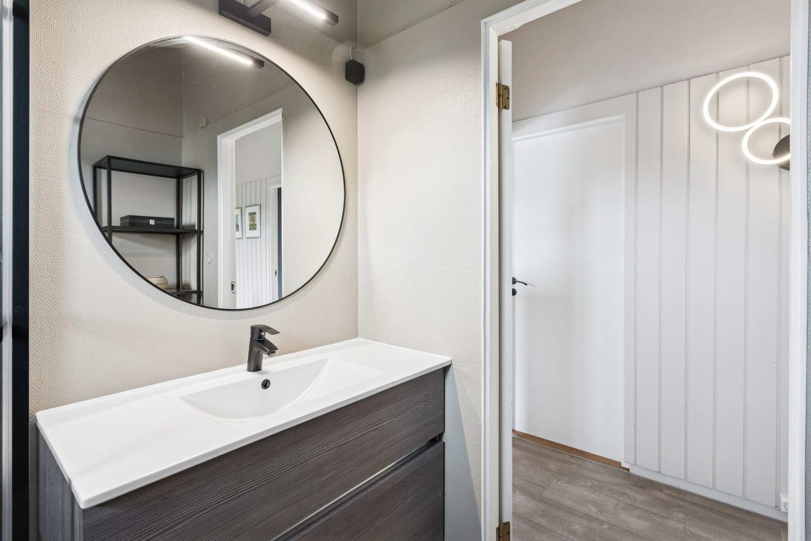 Baderom i 1. etasje med belegg på gulv og vegger med malte plater og malt strie. Her er det dusjkabinett og baderomsinnredning med heldekkende servant og speil med belysning over. Varmekabler i gulv. Galleribilde