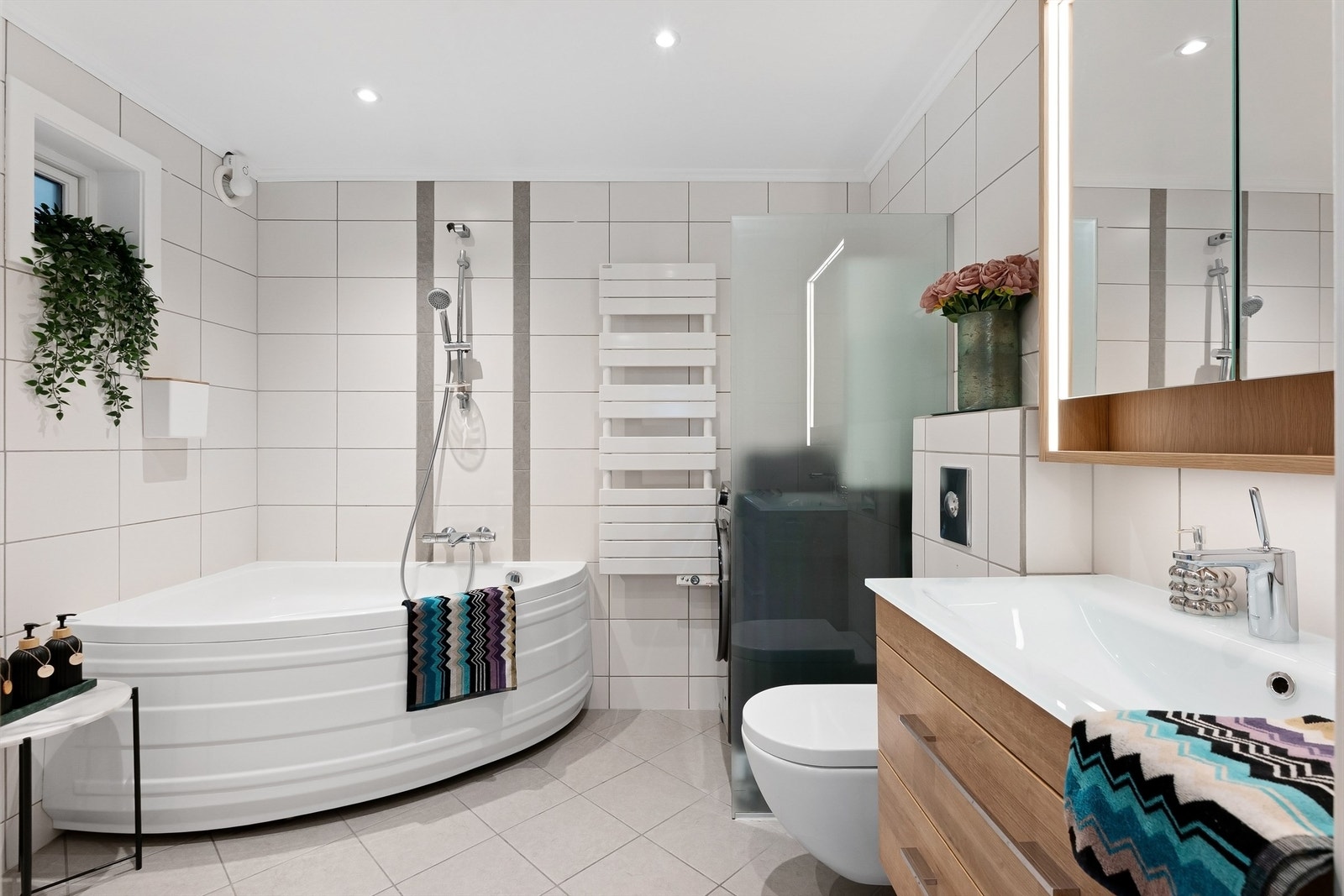 Pent baderom med fliser på gulv med gulvvarme, fliser på vegger og malt himling Galleribilde