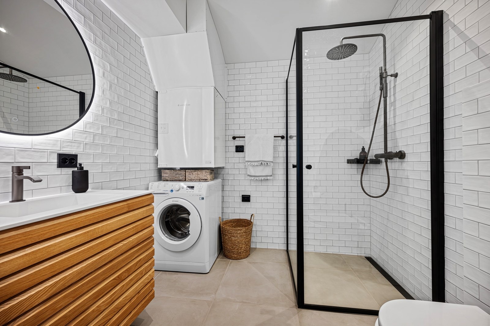 Lekkert bad/vaskerom som er utført med klassiske metrofliser og sorte detaljer for et tidløst uttrykk. Badet er helfliset med varme i gulv. Her er det også opplegg for vaskemaskin, og plass til tørketrommel. Galleribilde