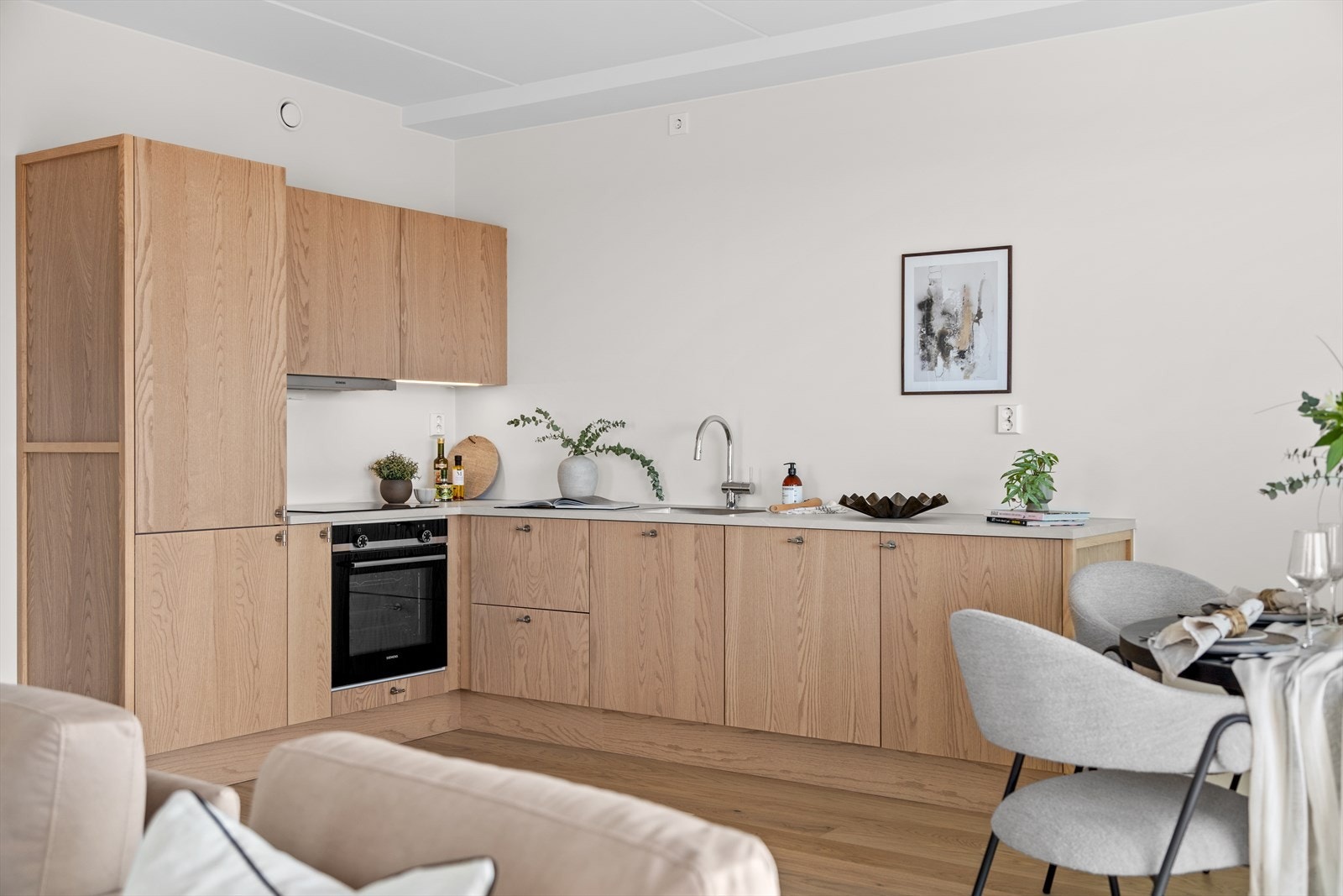 Her kan man stå og kokkelere i god kontakt med de som sitter rundt spisebordet i rommet og den helt åpne løsningen med stuen og naturlig plassering av spisestuebord gjør rommet lyst og hyggelig. Galleribilde