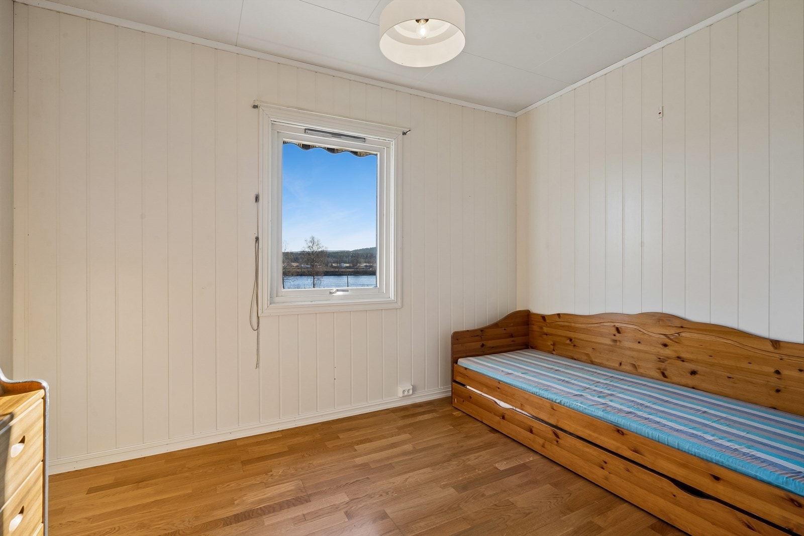 Boligen har tre soverom i hovedetasjen. Dette rommet har eikeparkett og utsikt mot Glomma. Galleribilde