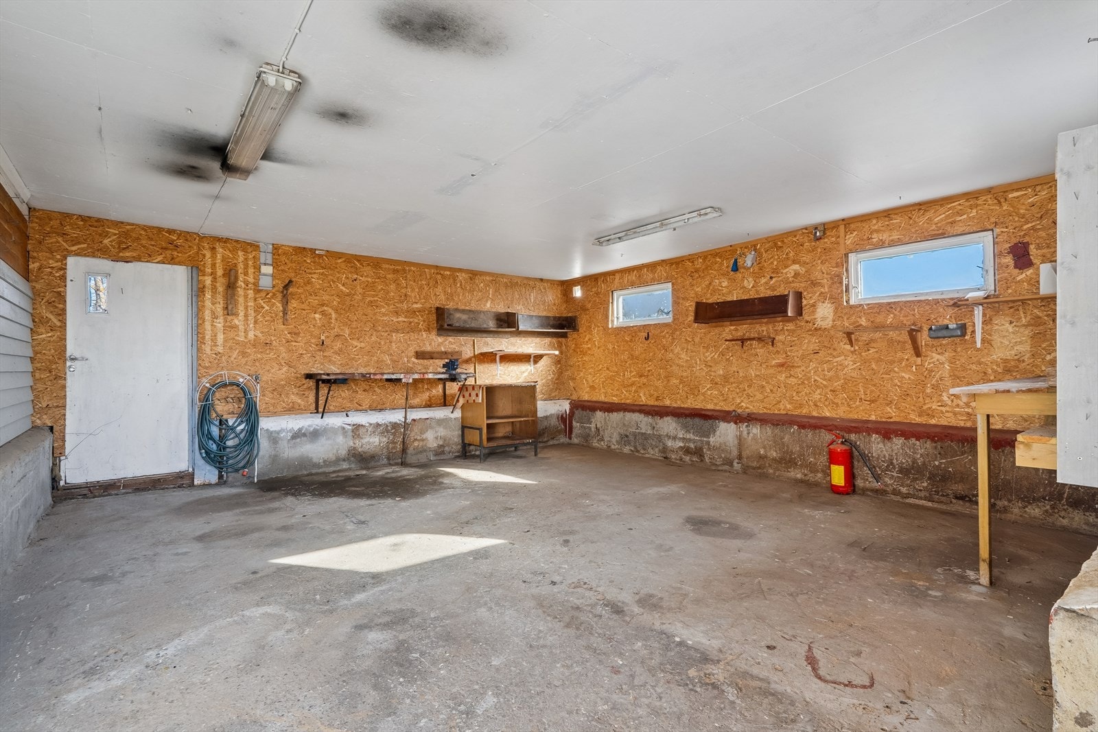 Det isolerte verkstedet har betonggulv, innlagt strøm og plassbygde benker og hyller. Galleribilde