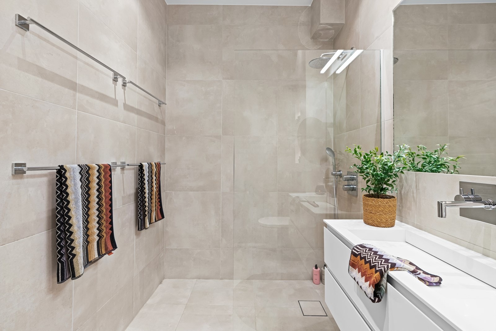 Badet er lekkert utført med beige store fliser og varmekabler i gulv. Takhøyden er generøs og sørger for en god romfølelse. Galleribilde