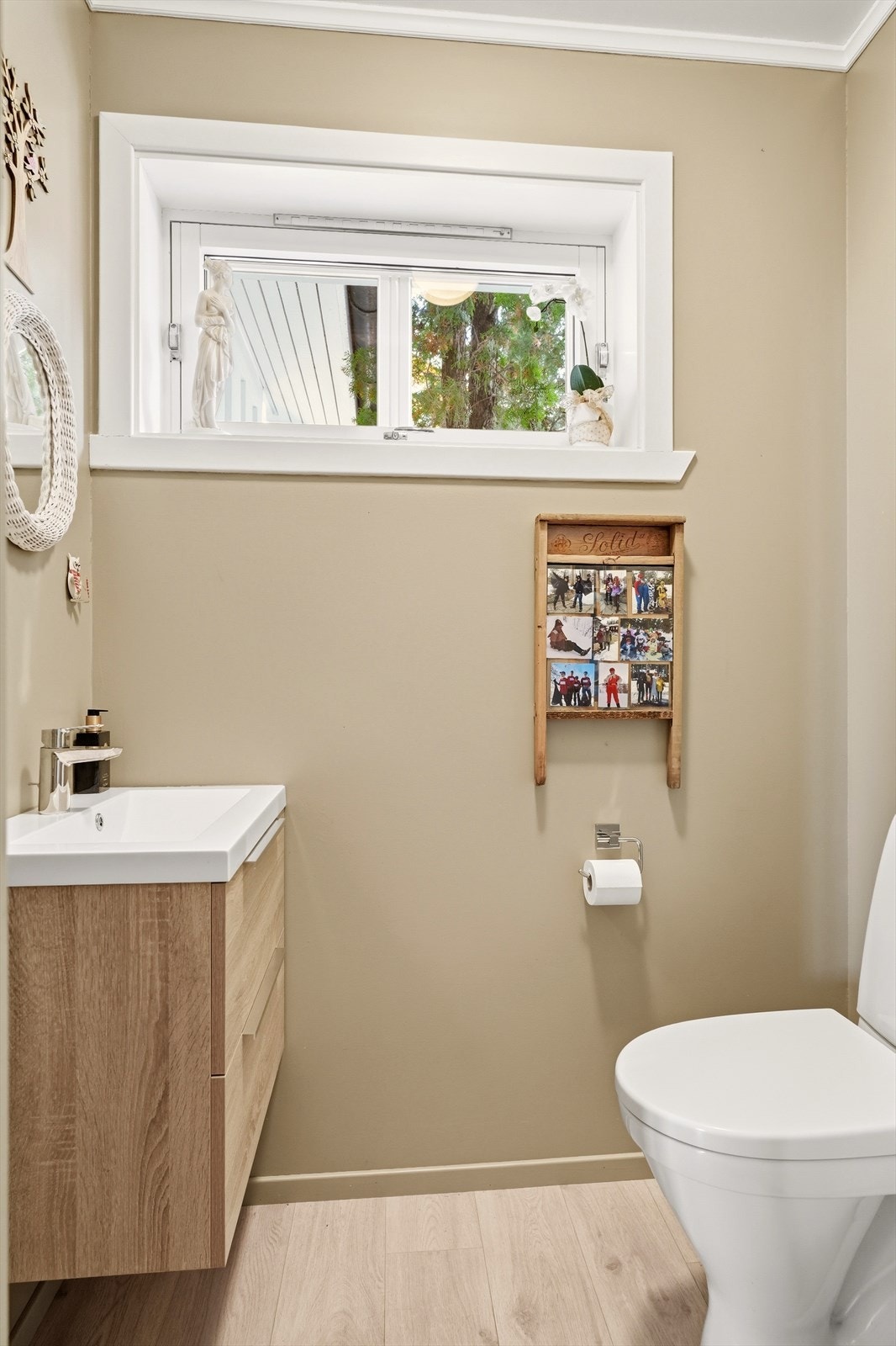 Lyst toalettrom med klosett og servant i innredning. Overflater med malte plater i himling og vegger samt laminatgulv Galleribilde