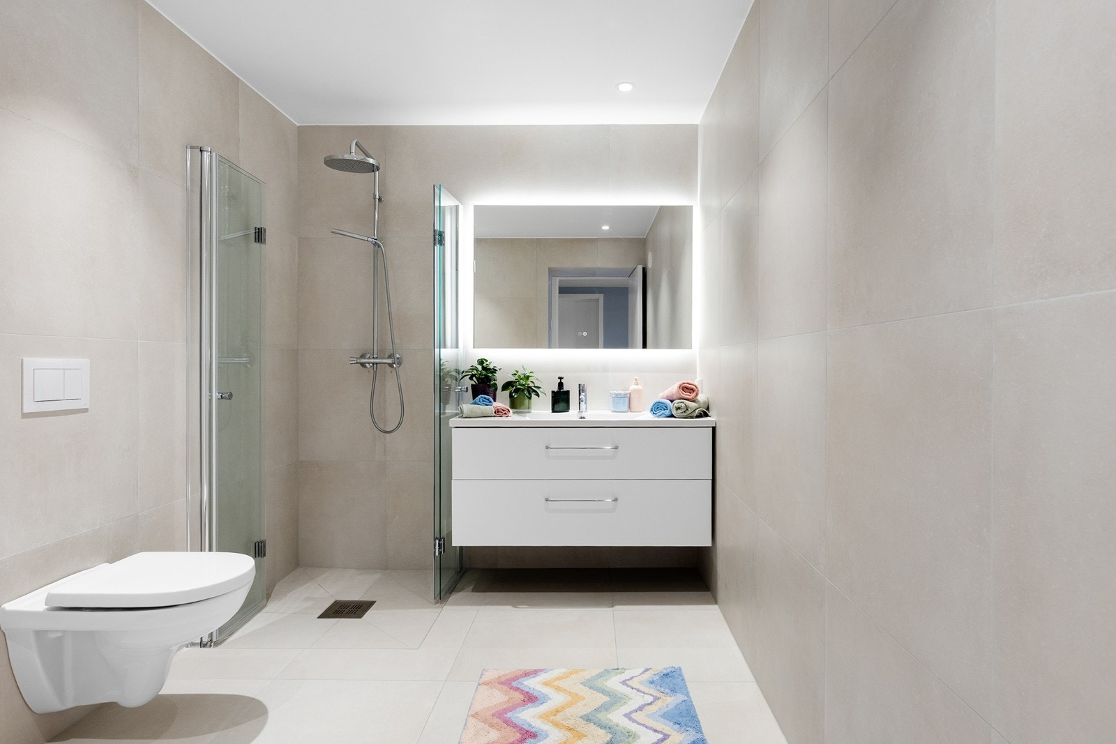 Lyst og fint flislagt bad med dusjhjørne, servant og wc Galleribilde