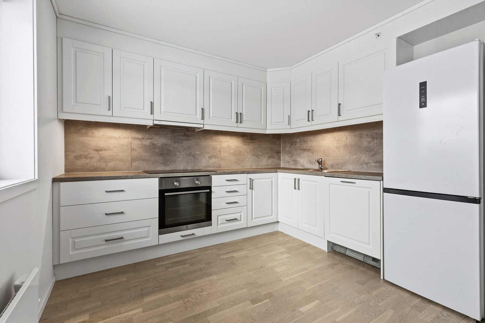 Montert plater mellom benk og overskap. Avsatt plass til kjøleskap. Galleribilde