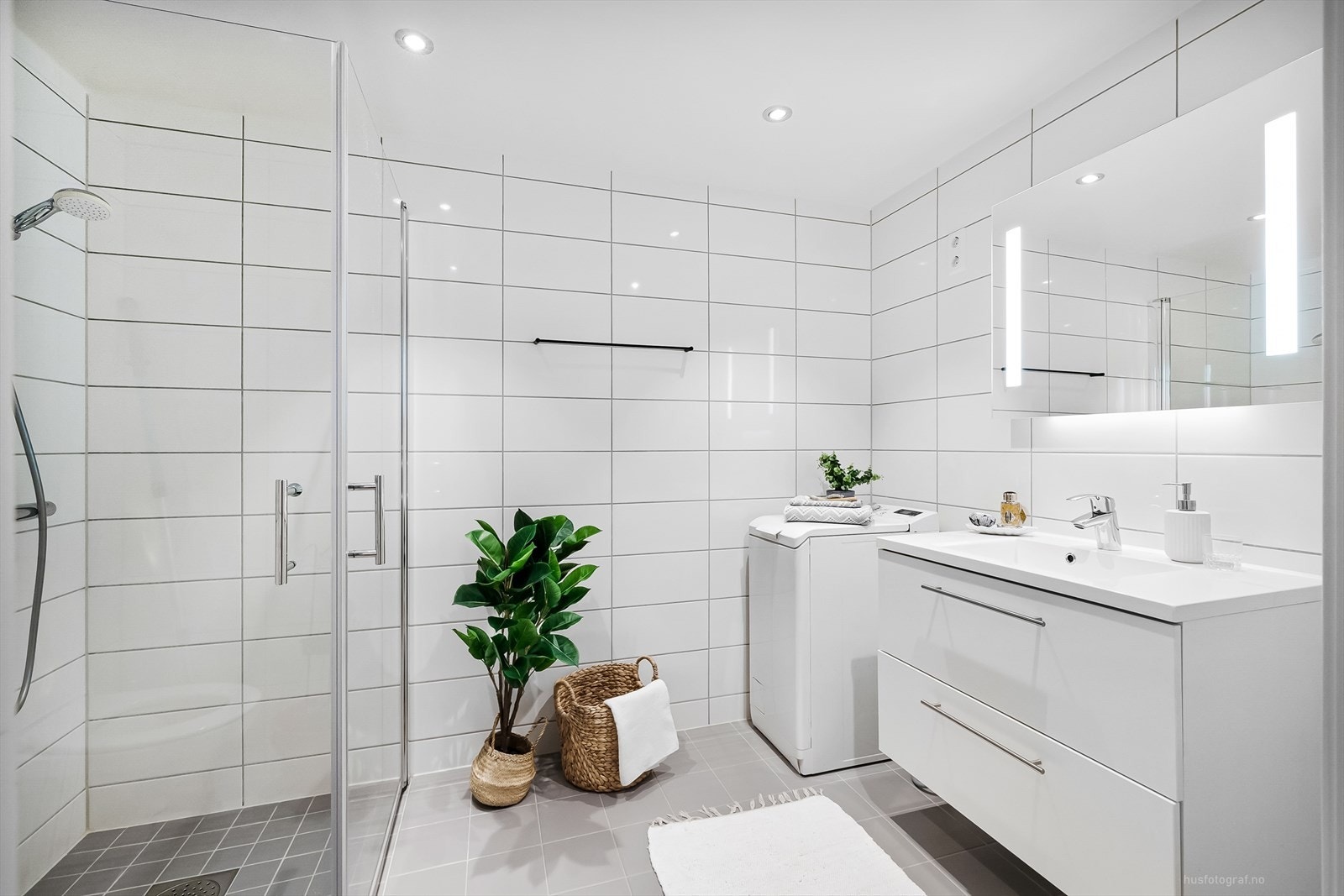 Lekkert og moderne baderom med opplegg for vaskemaskin, downlights i tak og varmekabler på gulv. Galleribilde