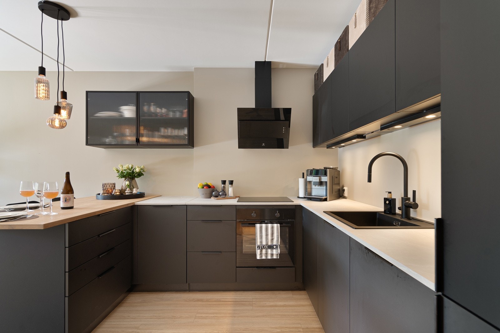 Kjøkkenet er elegant innredet med glatte fronter og benkeplate i kompositt, samt integrerte hvitevarer som stekeovn, induksjonstopp, kjøl/frys og oppvaskmaskin Galleribilde