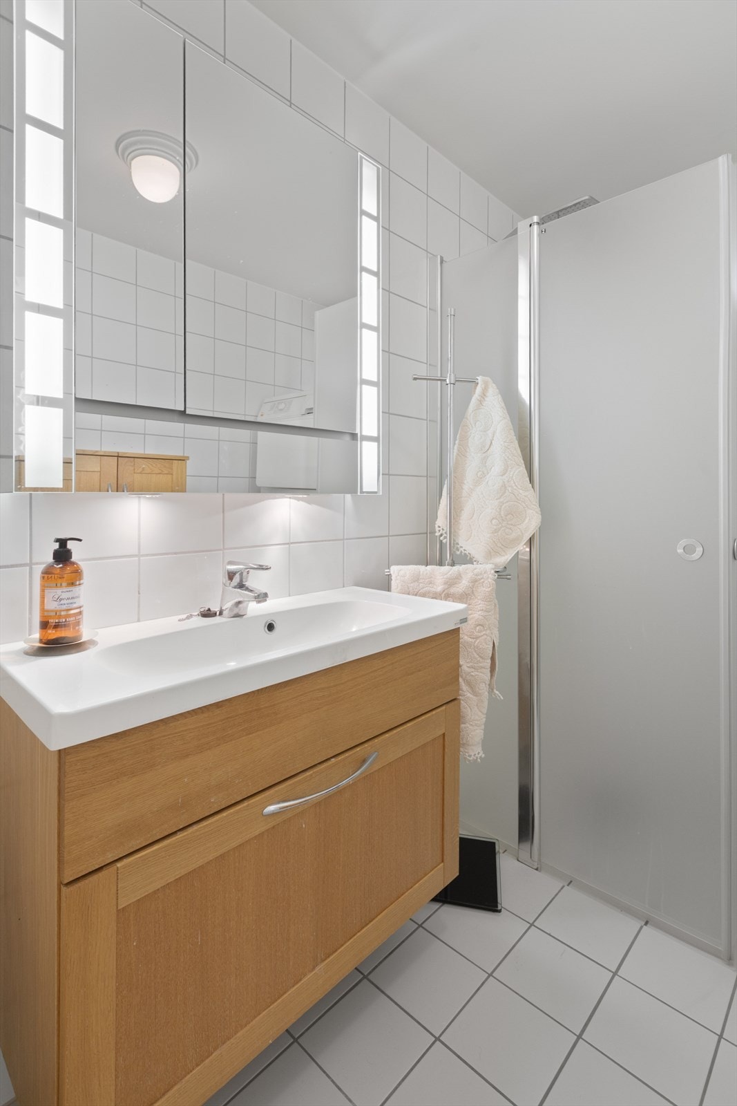Badet er godt utstyrt med toalett, servantinnredning, speilskap, samt en dusjnisje med glassdører. I tillegg er det plass til vaskemaskin og tørketrommel, noe som gir en praktisk og funksjonell løsning for hverdagslige behov. Galleribilde