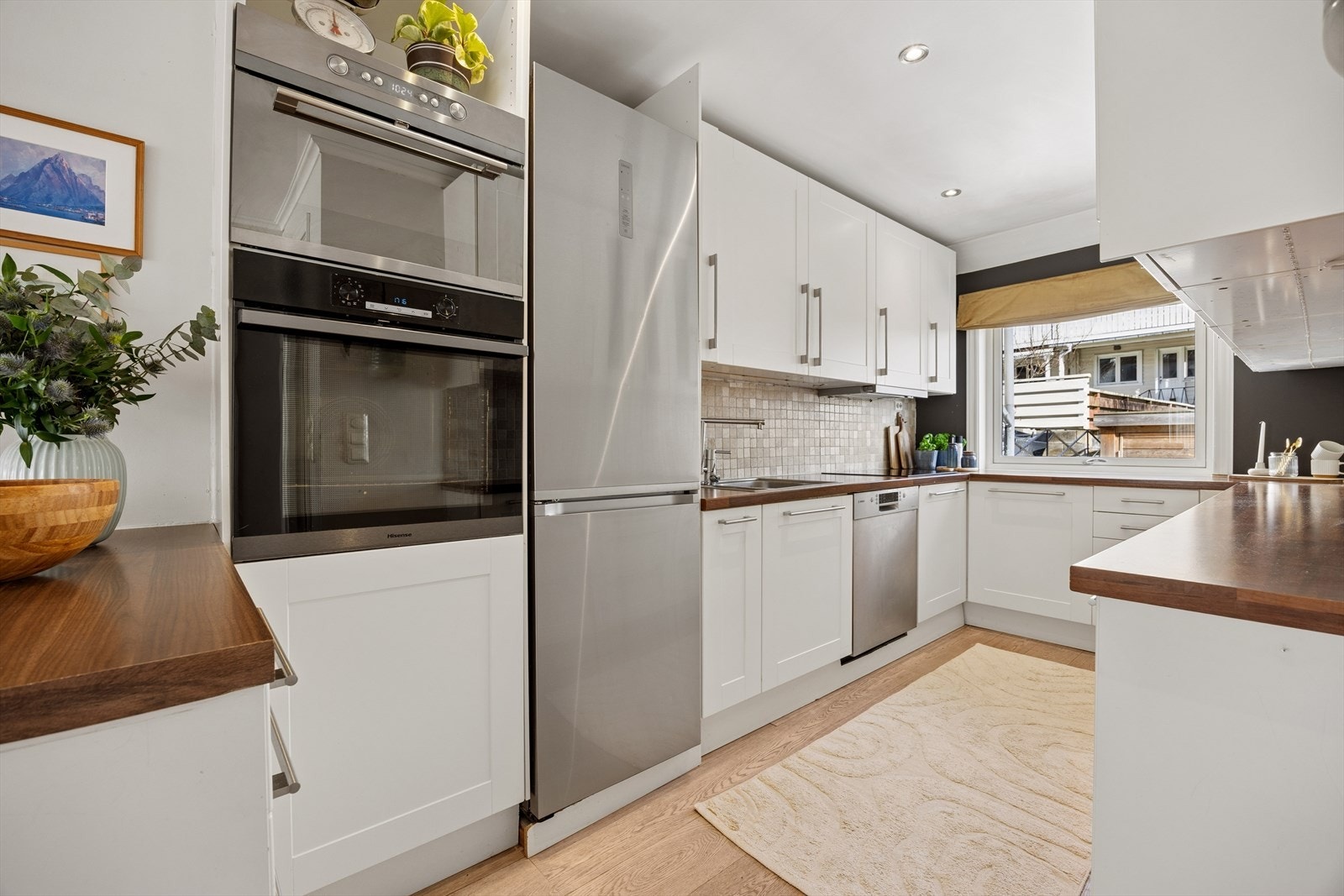 Kjøkkenet har lyse flater og er velutstyrt med god skap- og benkeplass. Her finner du integrerte hvitevarer som komfyr, mikro, oppvaskmaskin og platetopp. Galleribilde