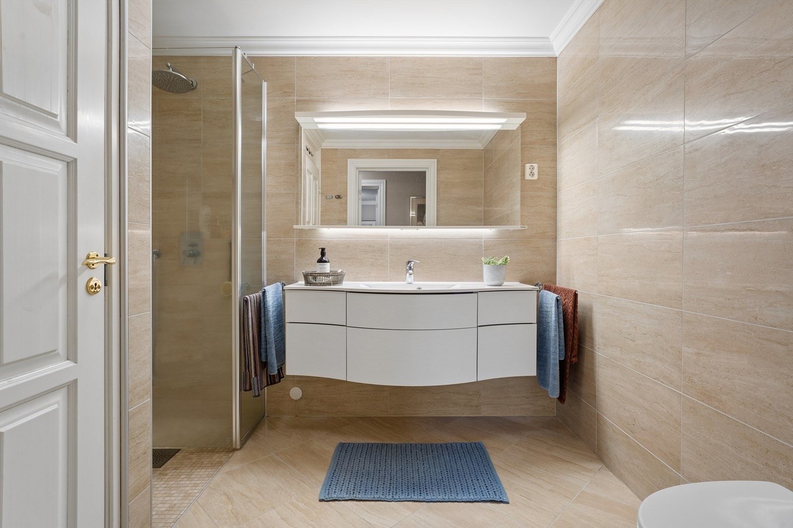 Det andre badet som er kombinert med vaskerom, ligger i underetasjen. Rommet har flislagte vegger og gulv med elektriske varmekabler, samt malt himling. Galleribilde