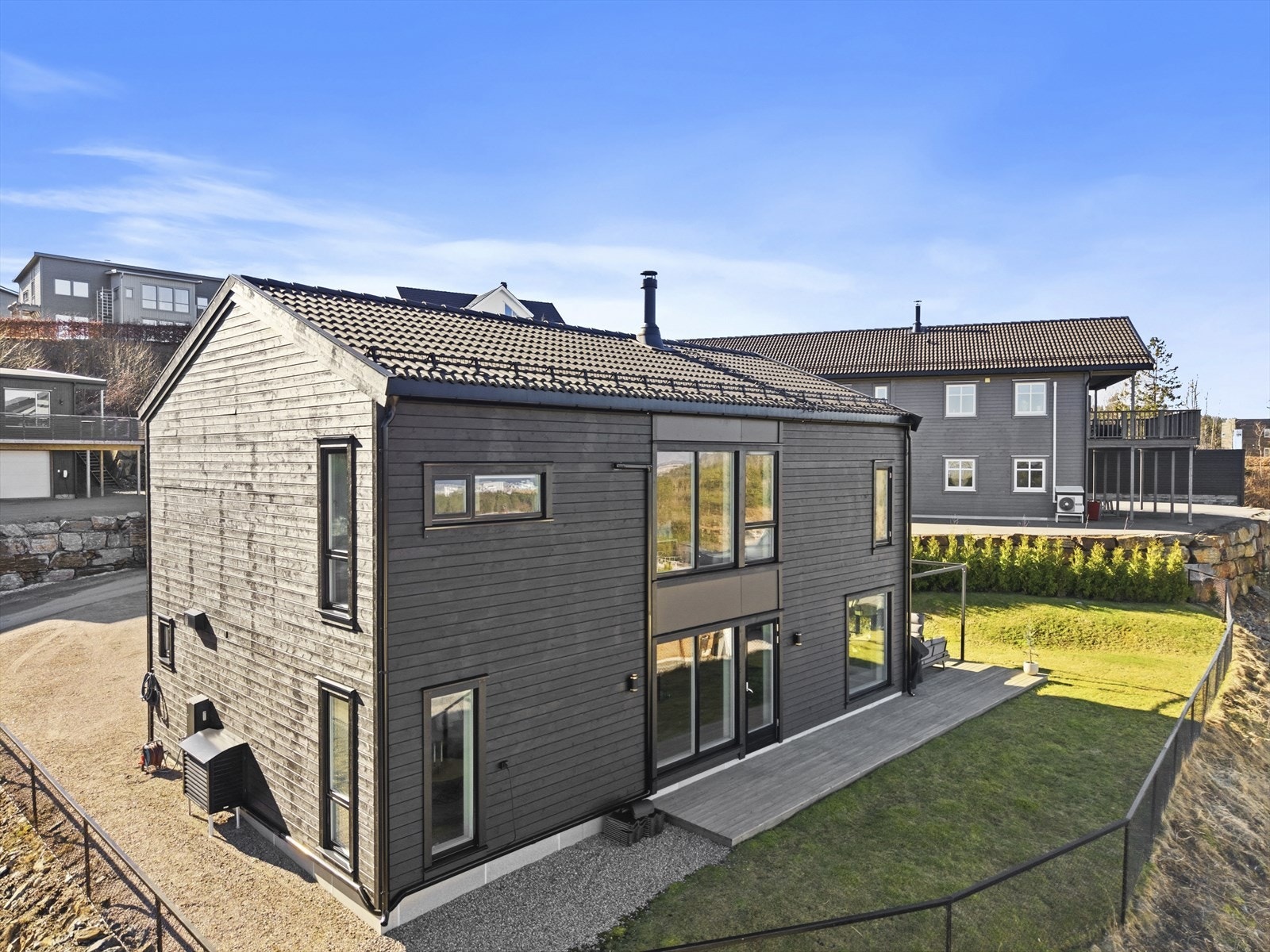 Hjørnetomt med koselig uteplass med terrasse og gressplen - Gruset gårdsplass med god plass til biloppstilling og elbillader Galleribilde