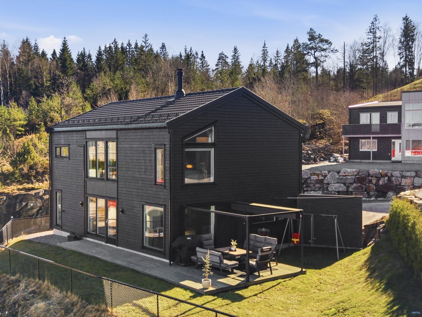 Skjermet uteområde med levegg, med terrasse og elektrisk pergola samt koselig gressplen med plass til lek og moro Galleribilde