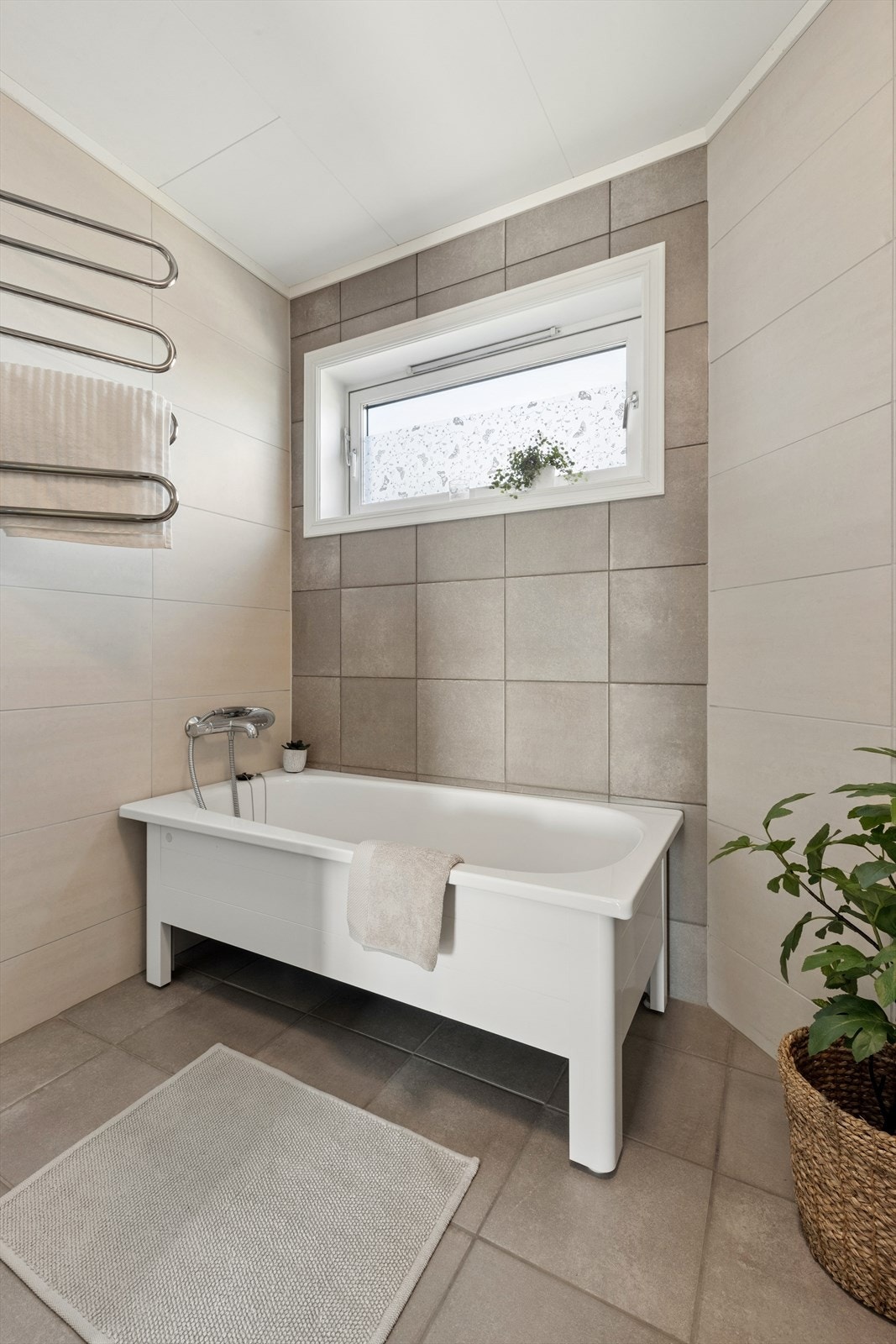 Rommet har flislagte overflater på vegger og gulv, med gulvvarme. Velværesone med badekar og elektrisk håndkletørker. Galleribilde