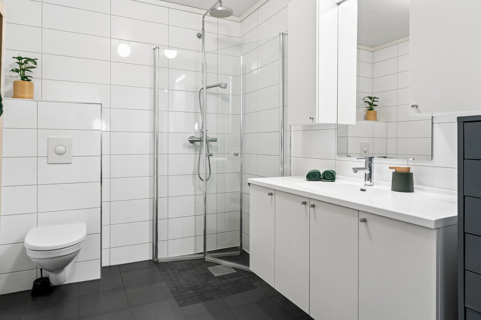 Badet er lyst og lekkert - med fliser i nøytralt fargeval. Regndusj gjer morgondusjen ekstra behageleg Galleribilde